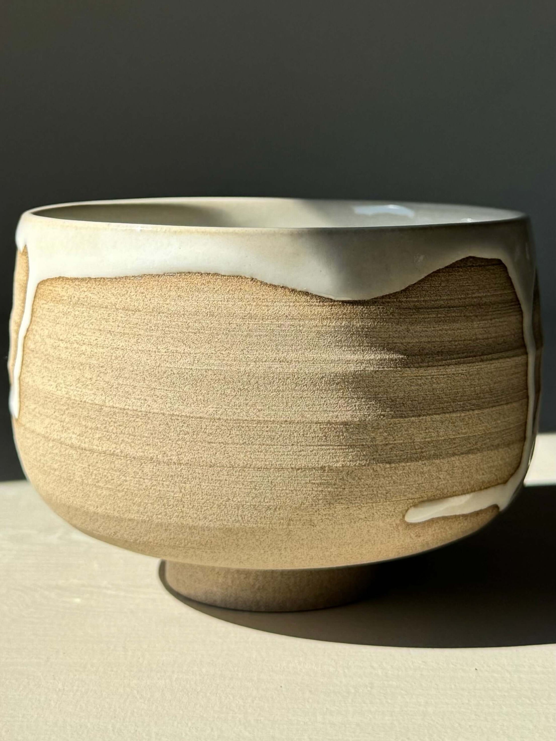 Handmade Matcha bowl from Yuki Series #09 with toffee clay base and glossy white glaze, featuring unique drip pattern.
