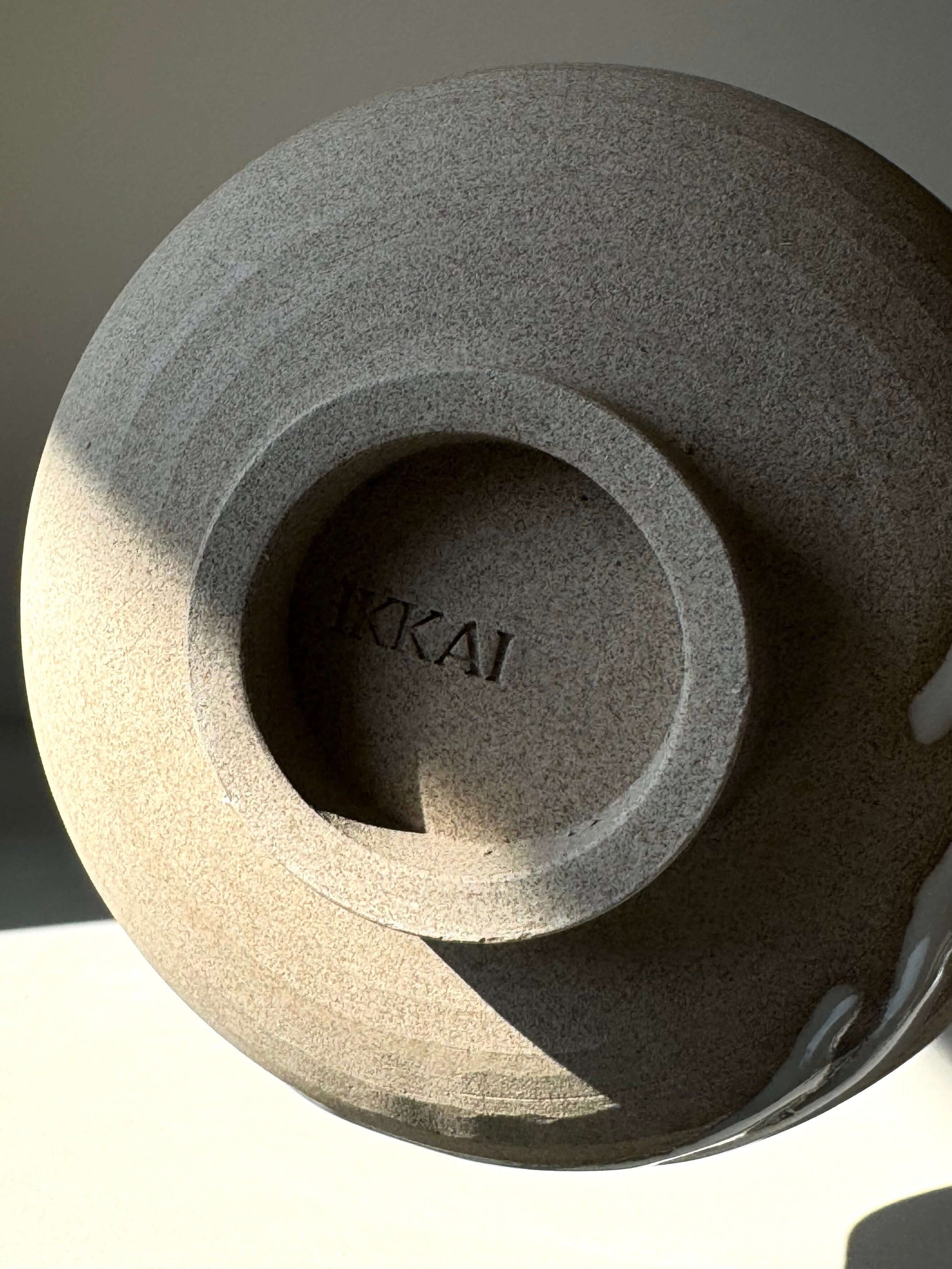 Underside of a handcrafted Matcha bowl with BKKAI engraving, showcasing natural clay texture and subtle glaze effects.