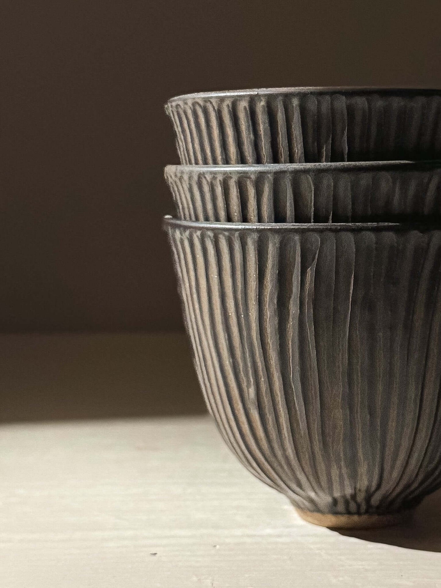 Stack of three Carved Yunomi Cup - Black Truffle showcasing handmade ceramics and pottery elegance.