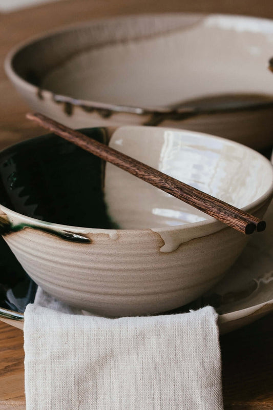 Wooden Chopsticks resting on a handmade ceramic bowl set, showcasing natural craftsmanship and elegance.