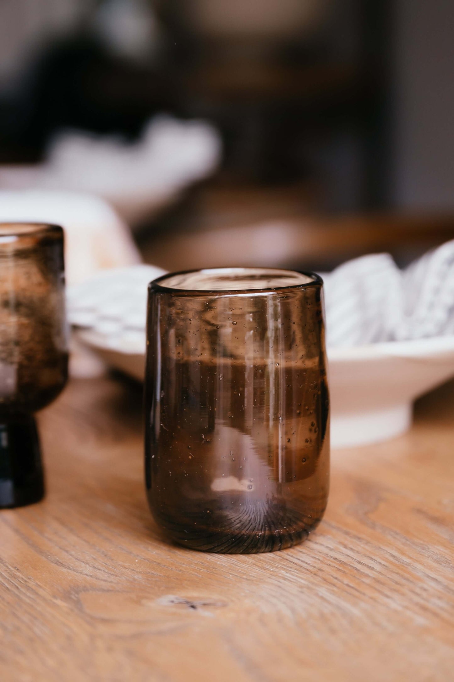 Brown Water Glass – Natural Tumbler with air bubbles on a wooden table, showcasing handmade ceramic design.
