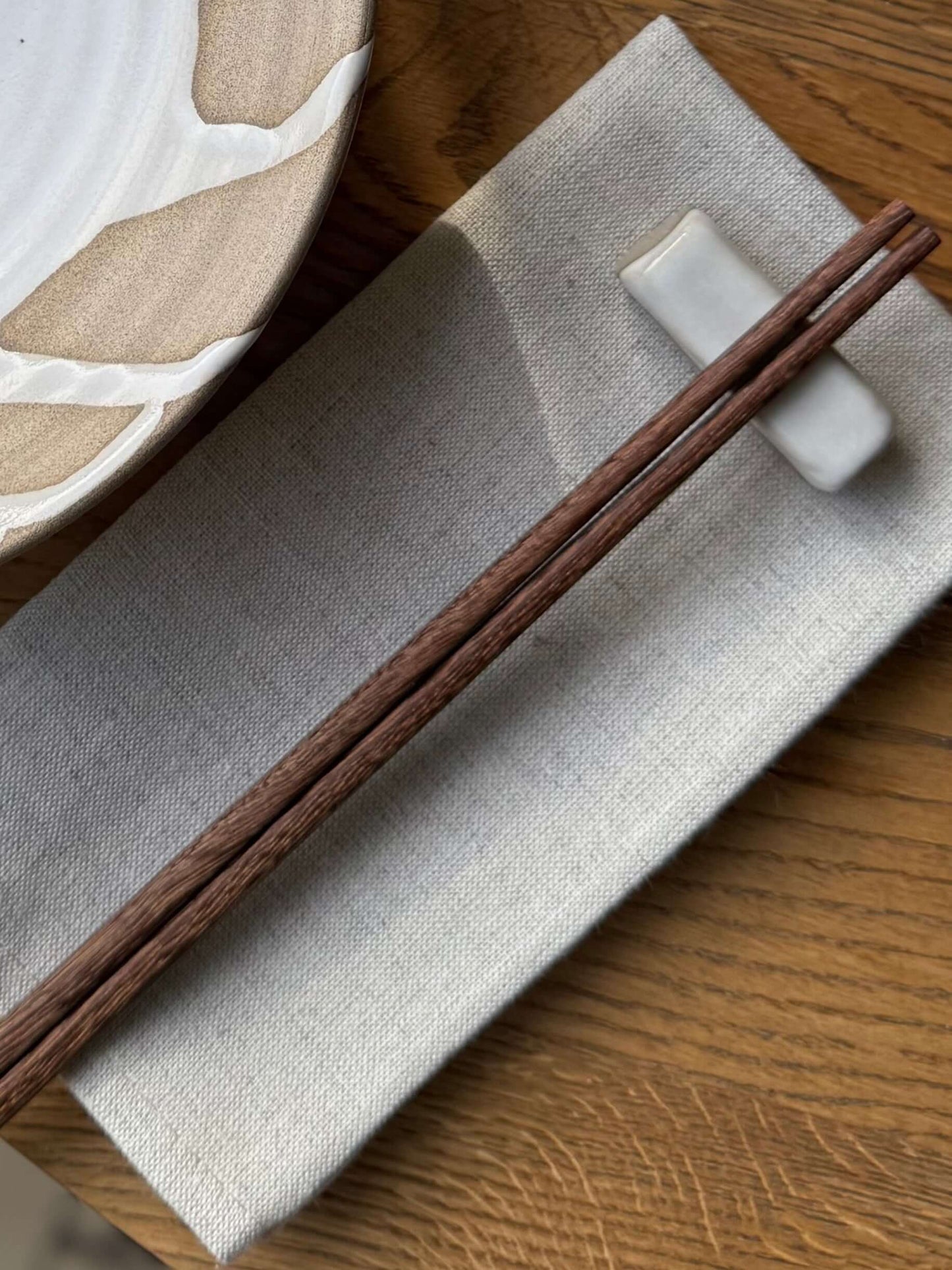 Handmade ceramic Chopstick/Spoon Rest – Yuki with chopsticks on a linen cloth, showcasing its unique white glaze design.