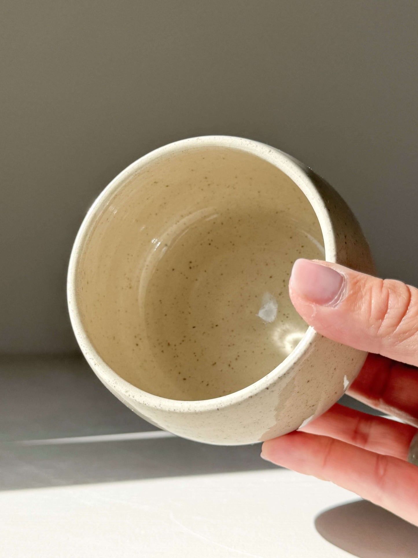 Hand holding Cups - Speckled Clear Glaze, handmade ceramic cup with soft, rounded shape and speckled glaze finish.