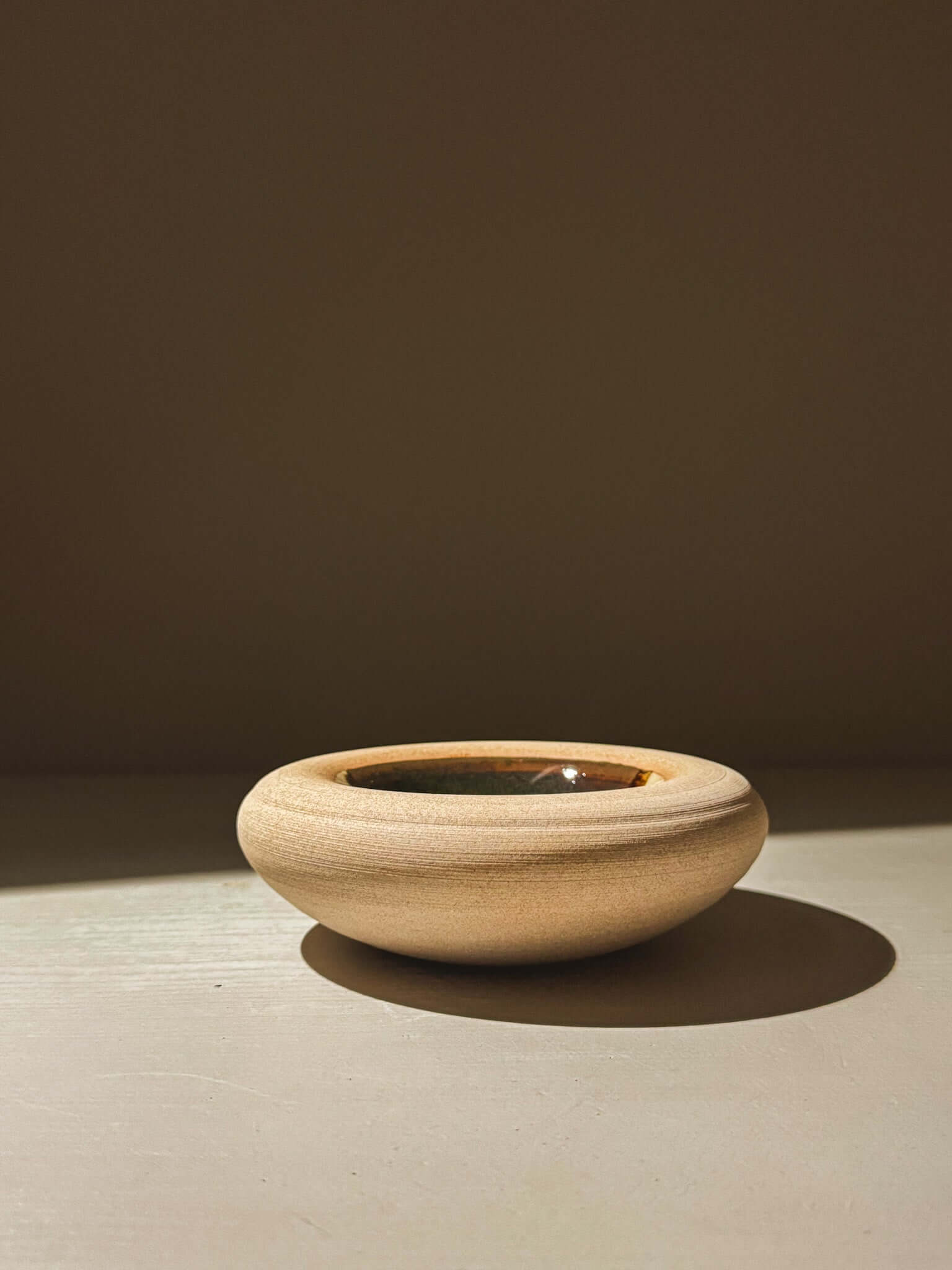 Handmade double-walled stoneware bowl with toffee-toned clay and clear tenmoku glaze from Inyo Series, featuring unique earthy tones.