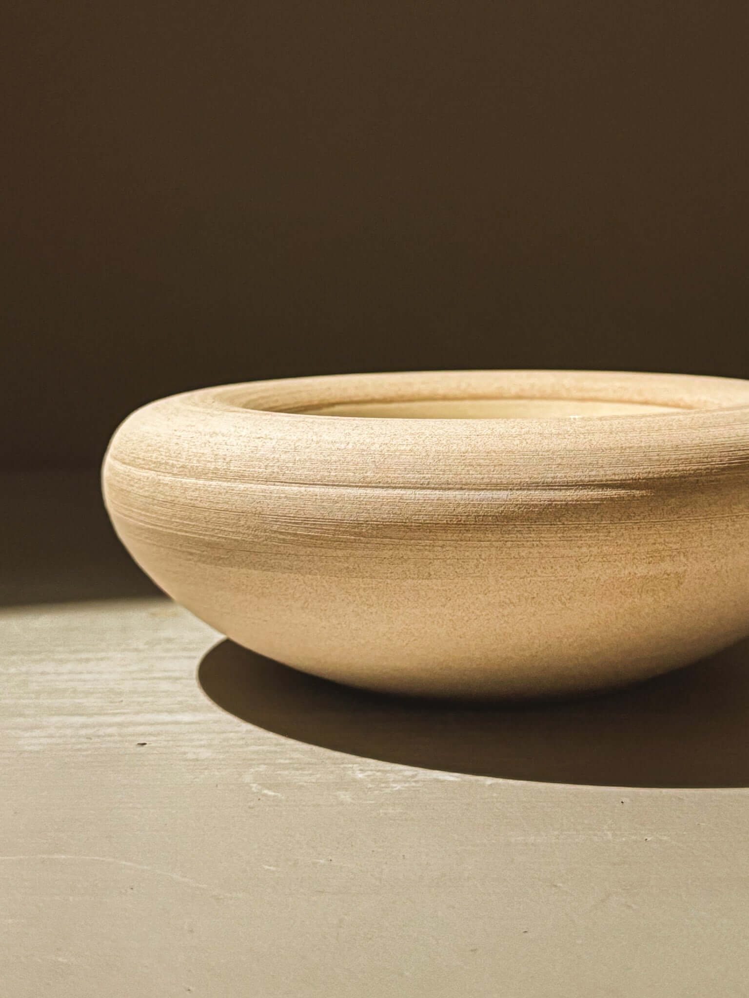 Handcrafted double-walled ceramic bowl from Inyo Series with toffee-toned raw exterior and unique glaze interior.