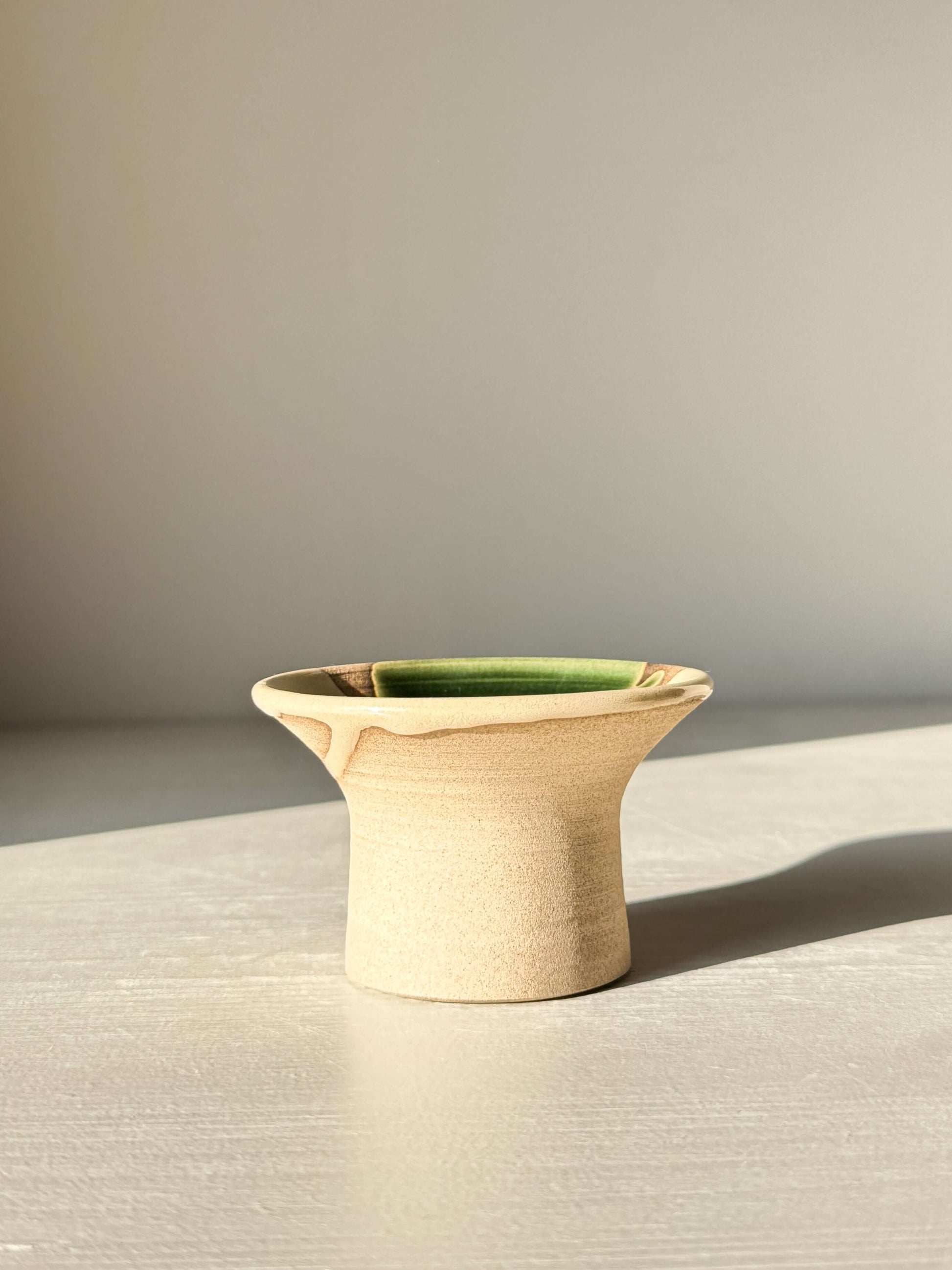 Egg Cup - Mori, a handmade ceramic with soft green Mori glaze on warm stoneware, wide rim design for holding eggs, photographed on a light surface.