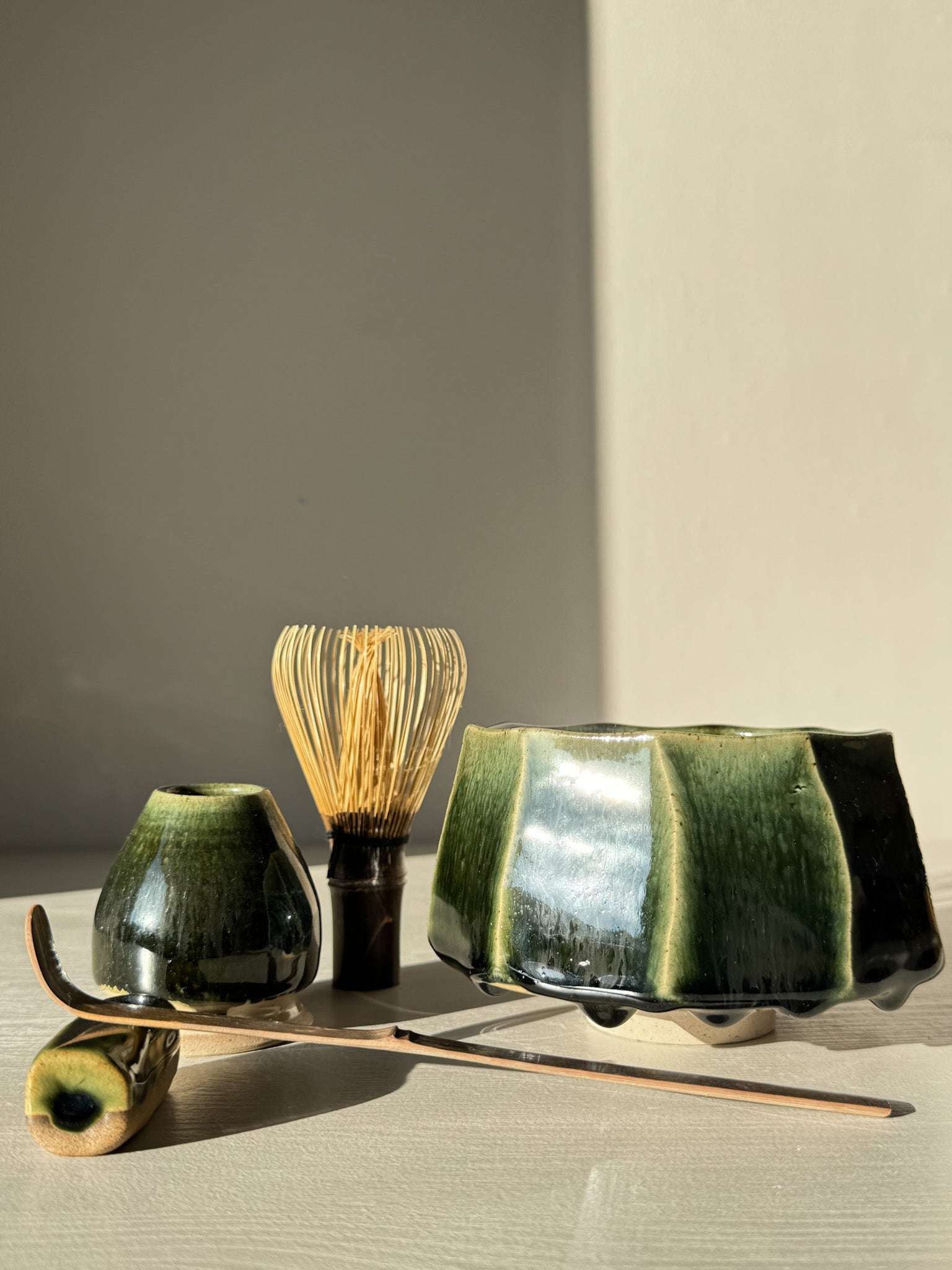 Faceted Matcha Bowl - Hinoki #03 with deep green glaze, matcha whisk, and accessories displayed elegantly in natural light