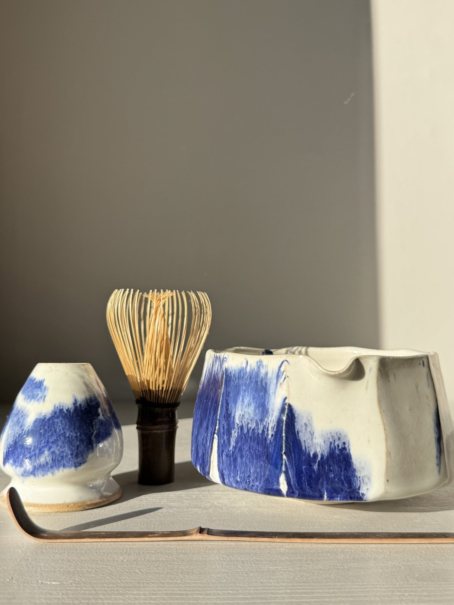 Faceted Matcha Bowl with Spout – White & Blue #02, featuring a faceted design with cobalt blue splash and spout, on a beige surface.