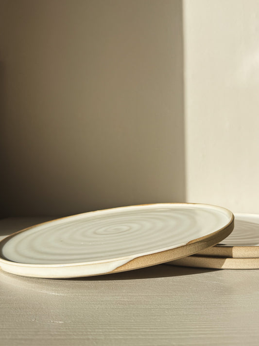Flat Round Plate – Yuki Series in soft white glaze over speckled stoneware, highlighting natural clay character and subtle beauty.