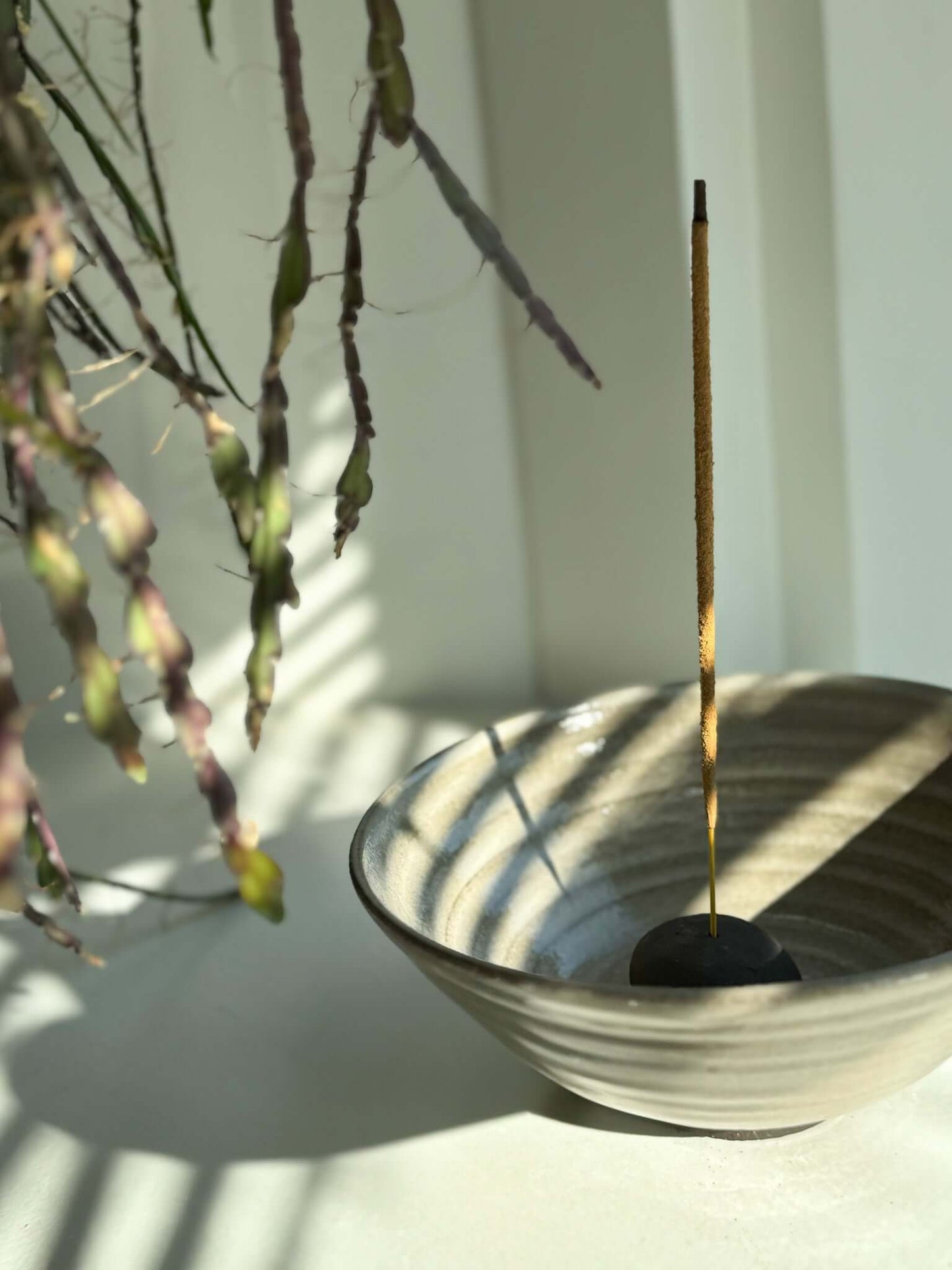 Handmade ceramic Incense Holder Pebbles with a single incense stick, adding an organic touch to a serene space.