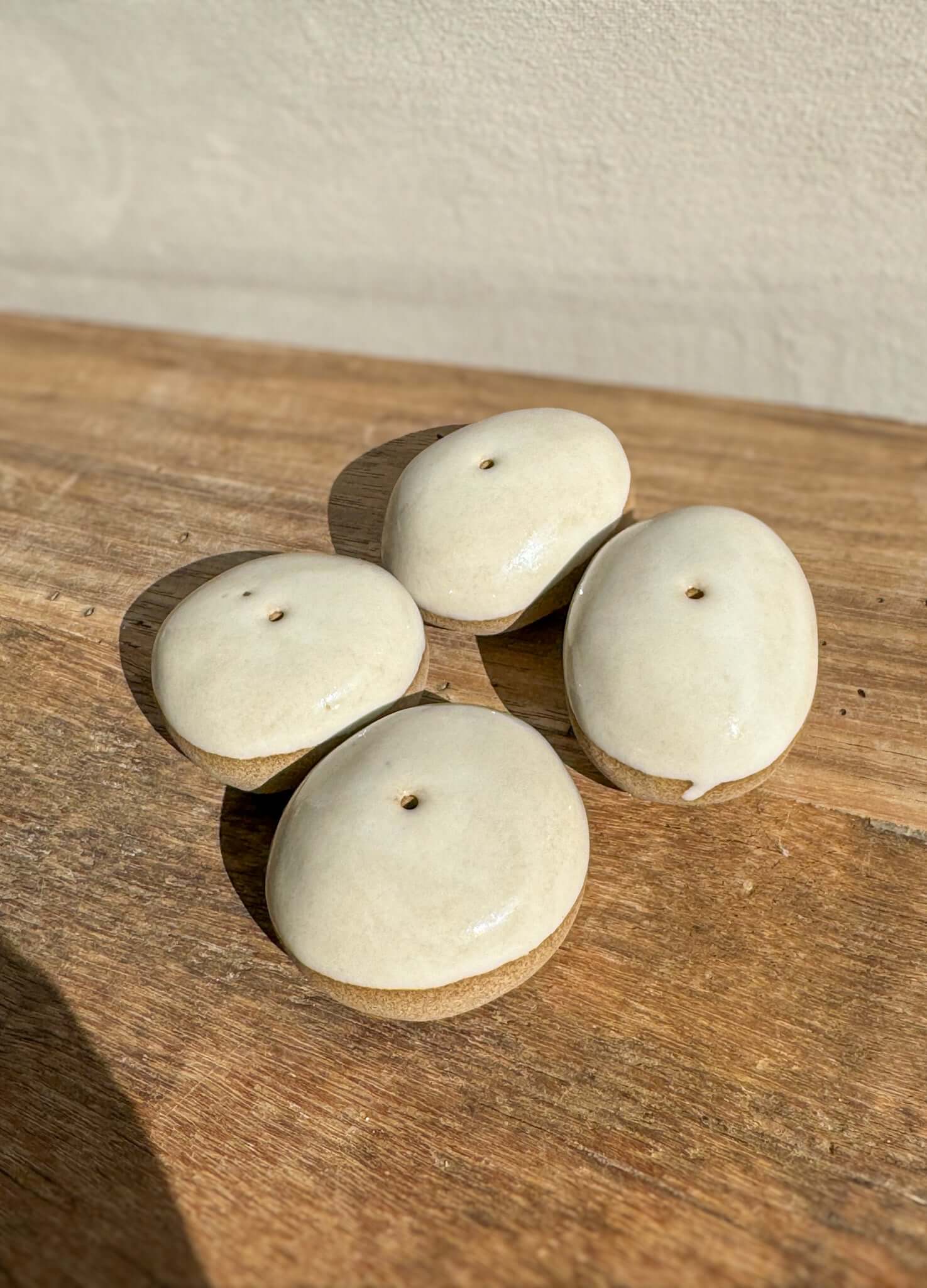 Handmade ceramic Incense Holder Pebbles with glossy and raw finishes on a wooden surface.