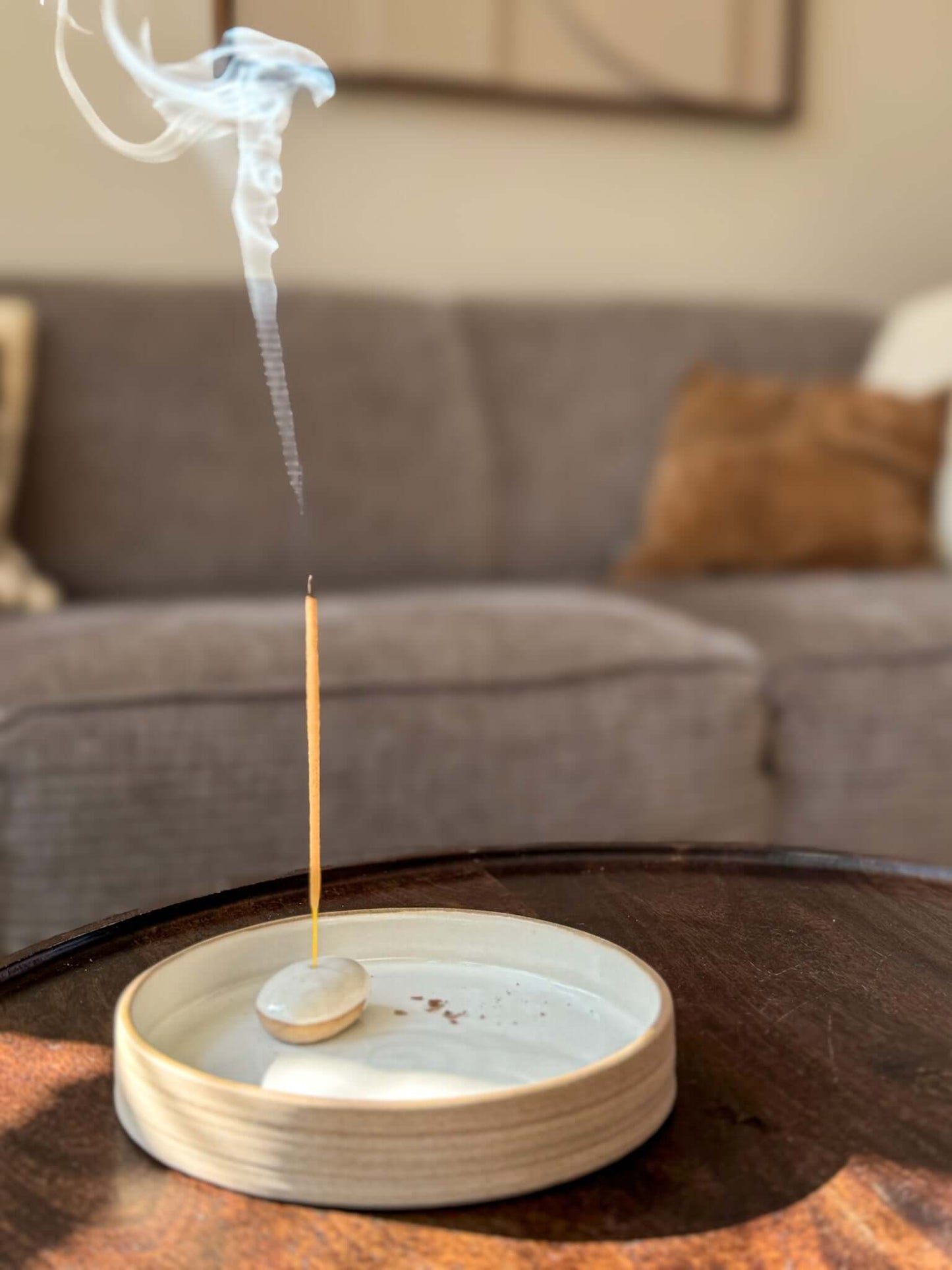 Incense Holder Pebbles made of handmade ceramic, featuring a burning incense stick on a wooden table, adding a serene touch to the room.