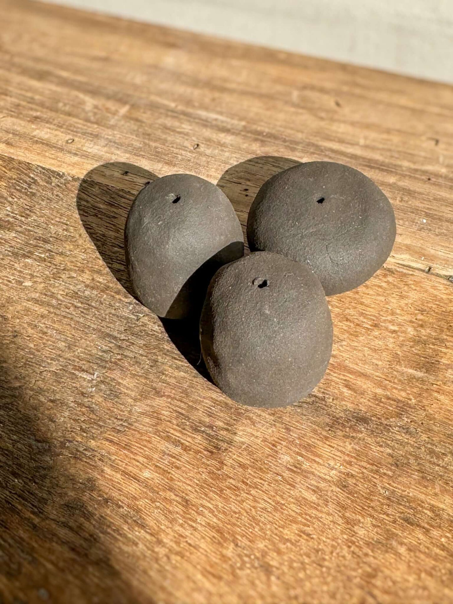 Handmade ceramic Incense Holder Pebbles resembling smooth river stones on a wooden surface, perfect for holding a single incense stick.