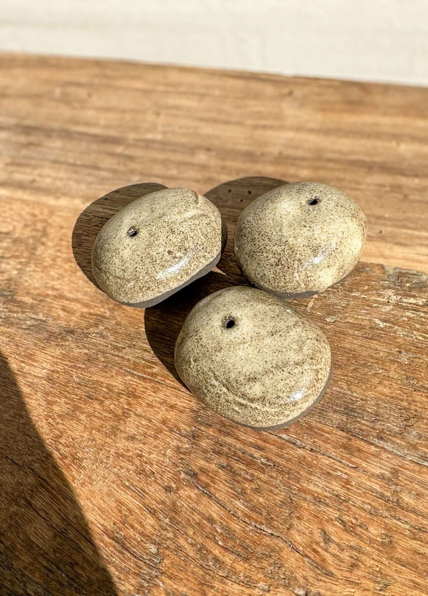 Handmade ceramic Incense Holder Pebbles on wooden surface, smooth river stone shape, natural tones, single incense stick slot, unique design.