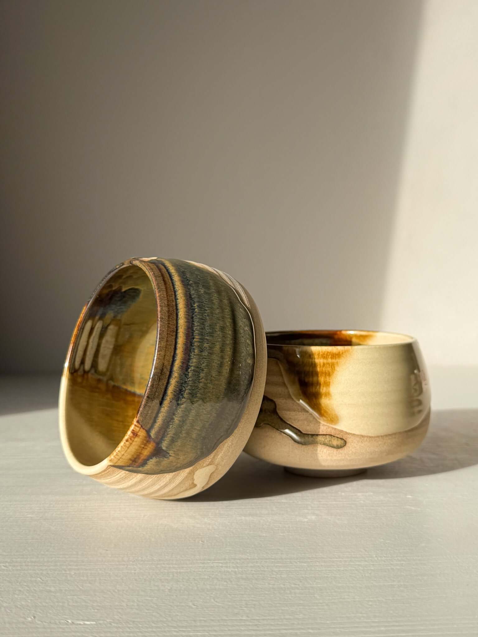 Handmade ceramic Coffee cups - Inyo showcasing contrasting glazes with rounded form, highlighting deep tenmoku and clear finishes.