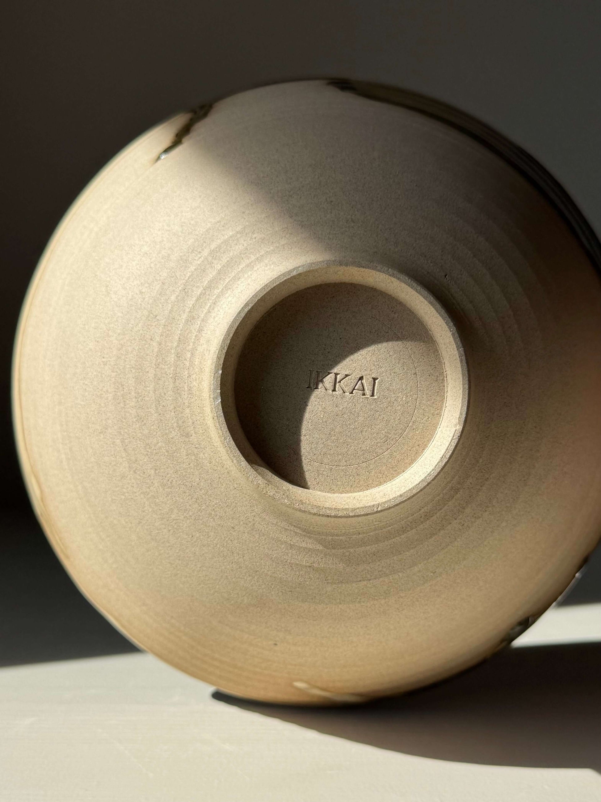 Base of handmade ceramic Salad/Pasta Plate – Inyo with stamped details, showcasing a blend of clear glaze and Tenmoku accents.