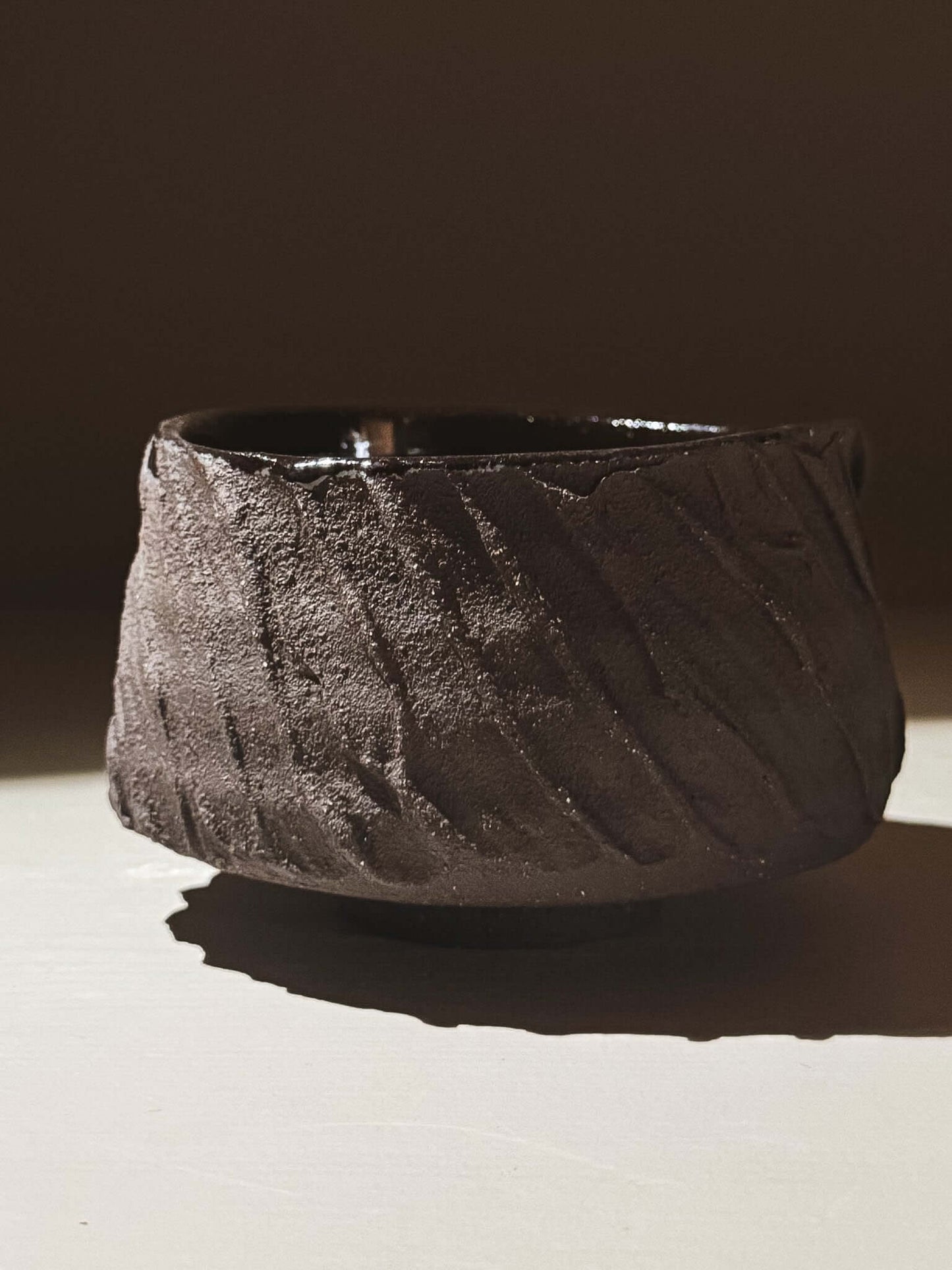 Kuro Matcha Bowl #04 with textured dark brown slip and glossy dark glaze interior, inspired by volcanic stone and earthy tones.