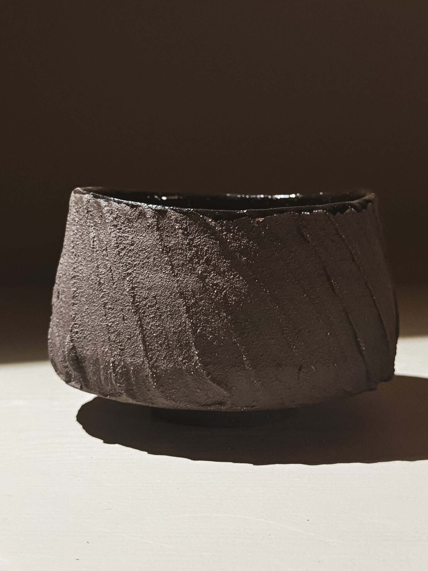 Kuro Matcha Bowl #07 with volcanic stone texture and deep glossy interior, showcasing earthy dark natural tones.