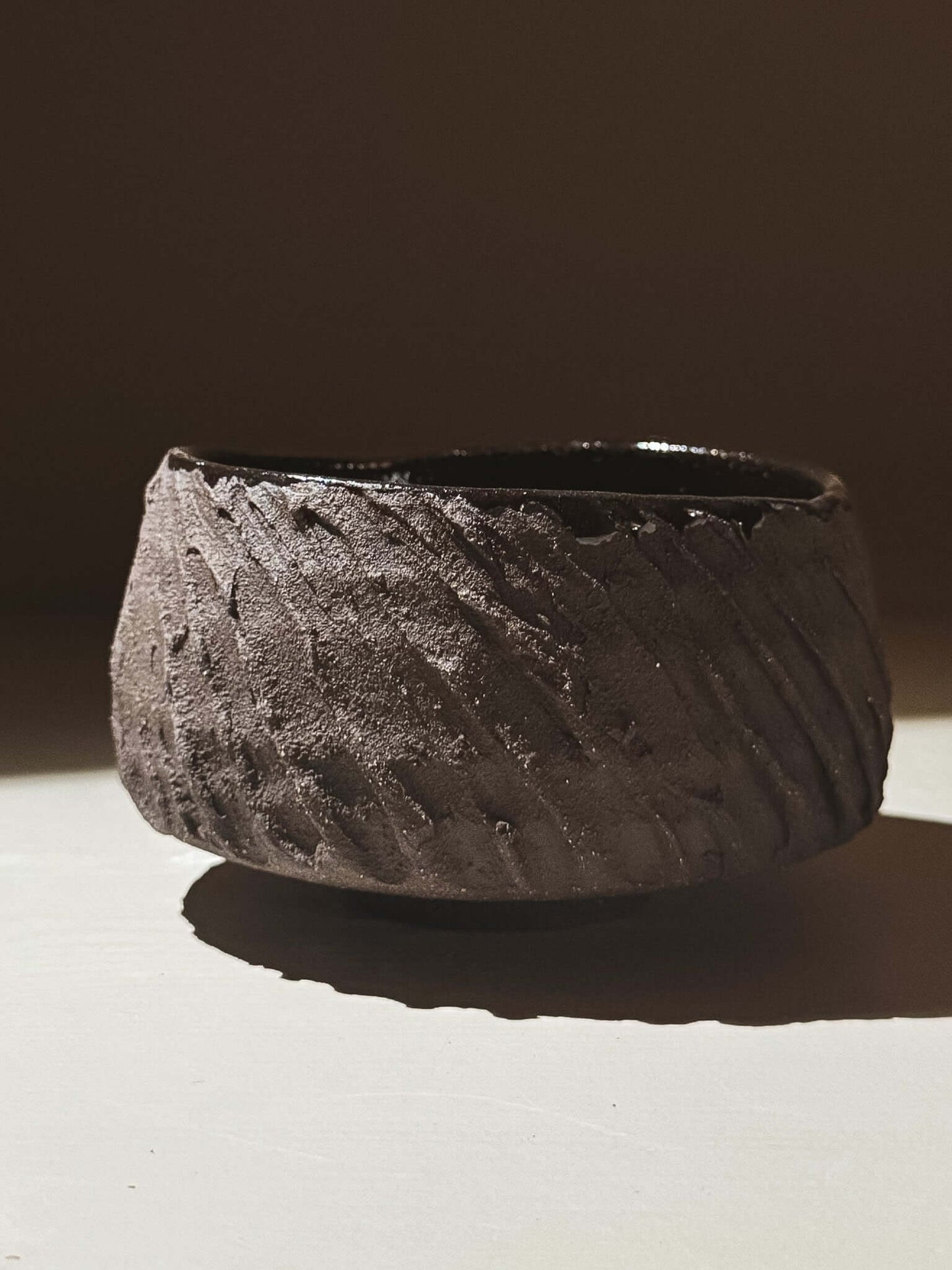 Kuro Matcha Bowl #08 with textured dark brown exterior and glossy dark interior, inspired by volcanic stone and natural tones.