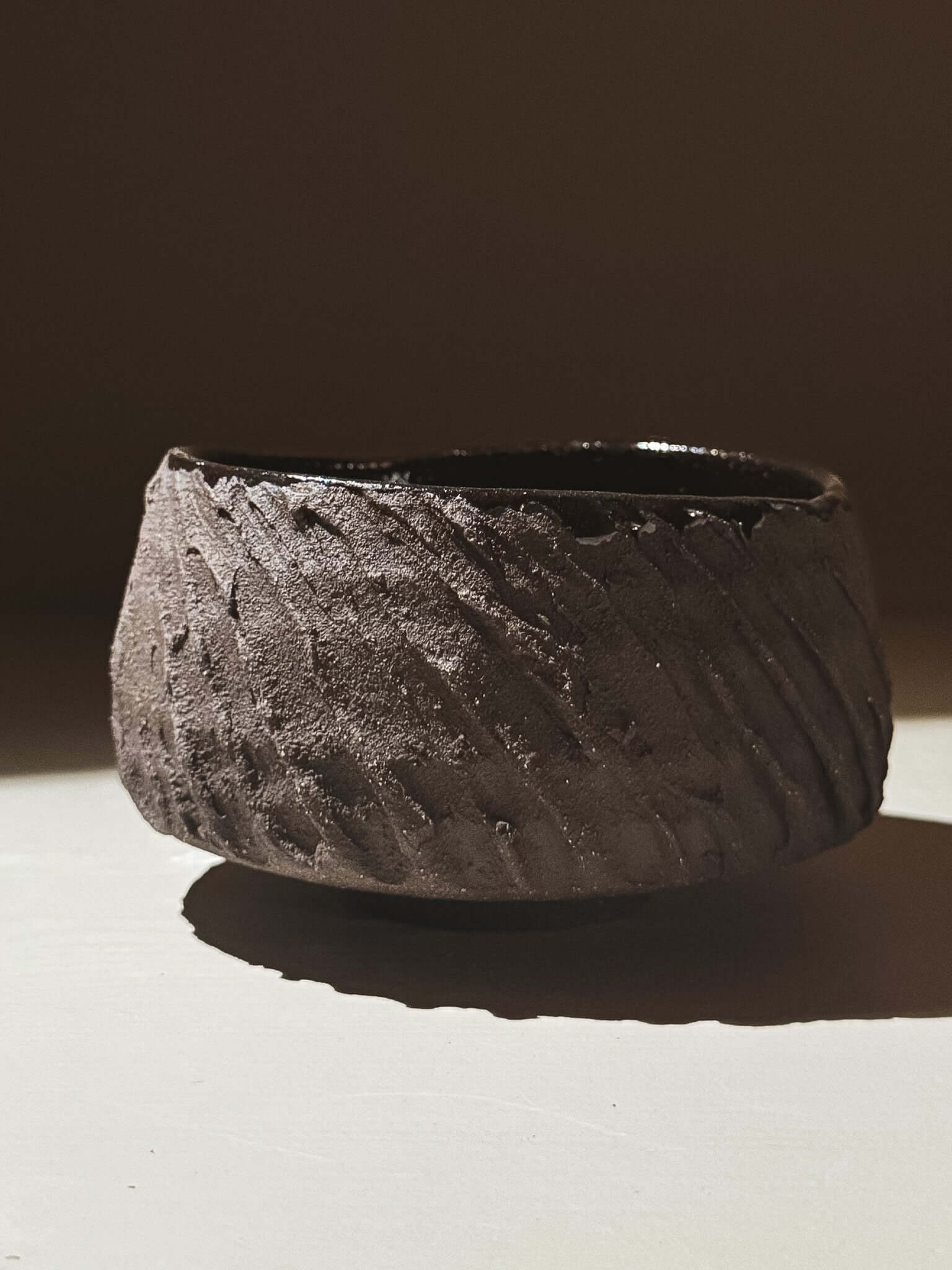 Kuro Matcha Bowl #08 with textured dark brown exterior and glossy dark interior, inspired by volcanic stone and natural tones.