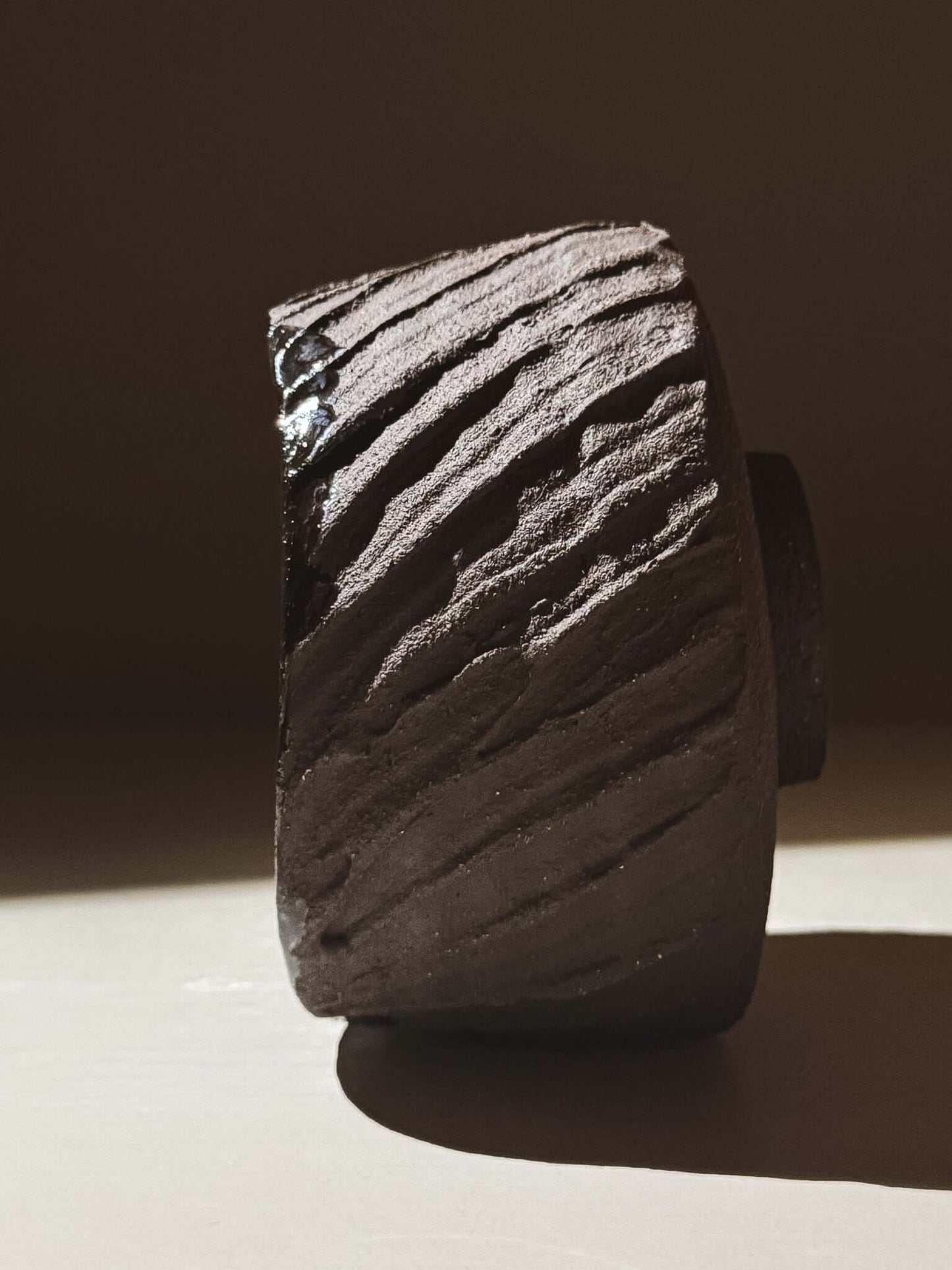 Side view of Kuro Matcha Bowl #05 with textured dark brown exterior inspired by volcanic stone and glossy interior.