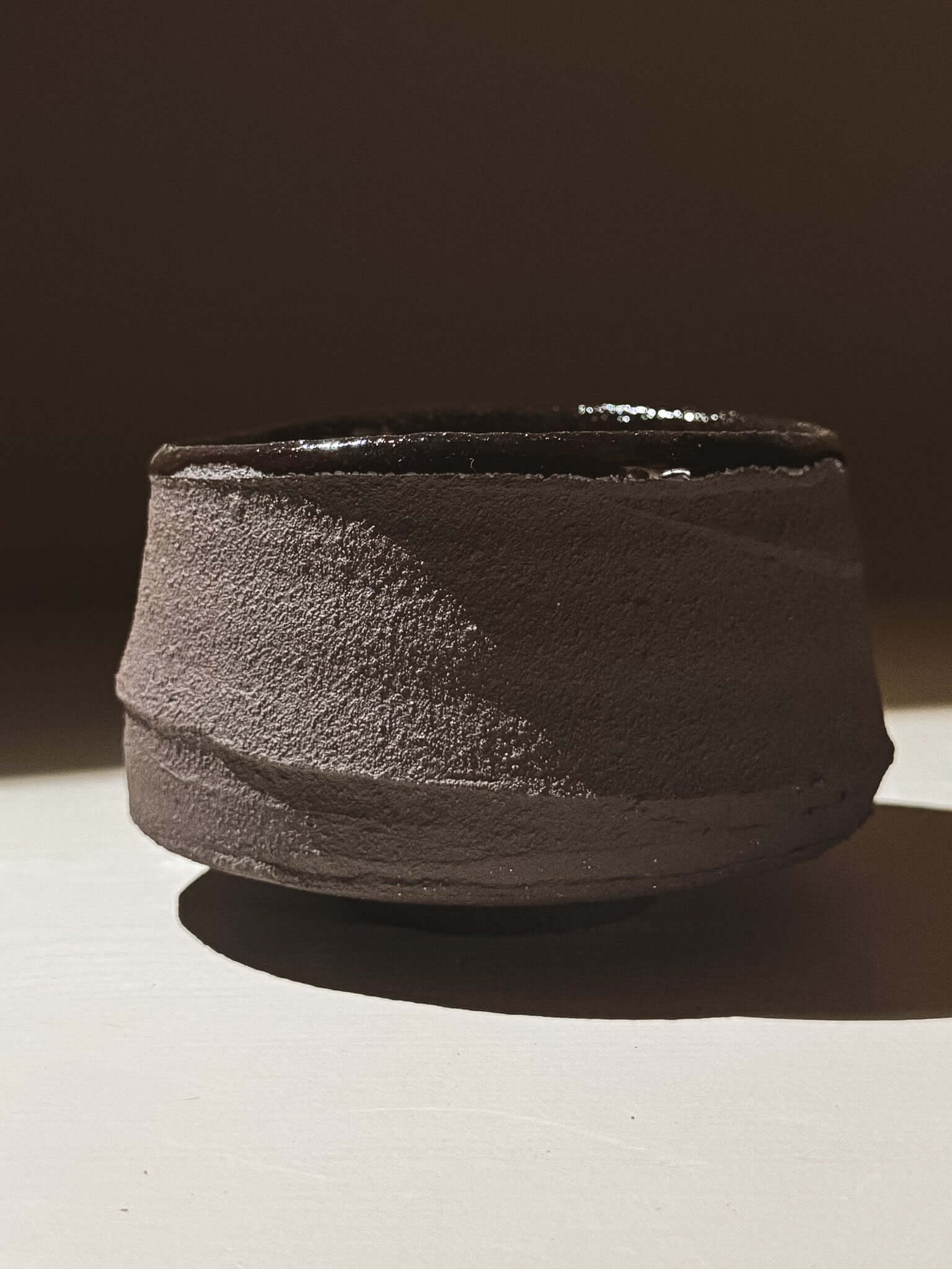 Kuro Matcha Bowl #09 with textured dark brown exterior and glossy dark interior, inspired by volcanic stone and earthy textures.
