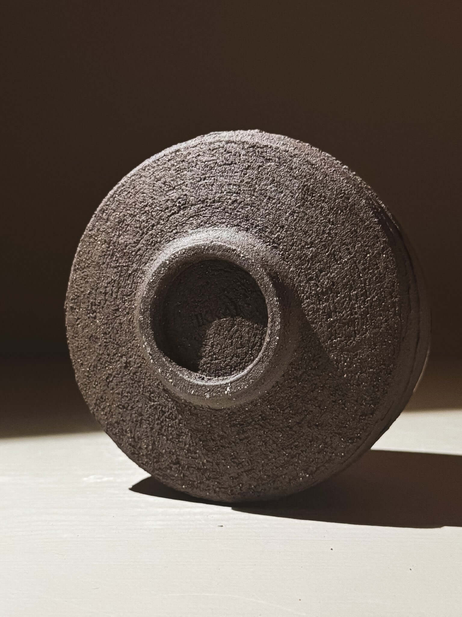 Kuro Matcha Bowl #10 with textured dark brown exterior inspired by volcanic stone and glossy dark interior on a light surface.