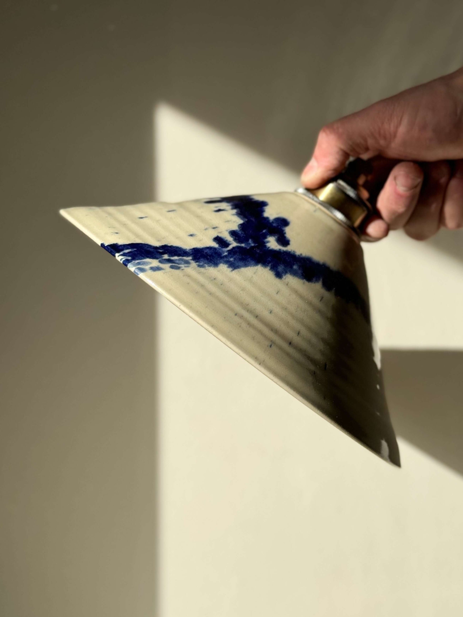 Close-up of a handmade ceramic lamp shade from the Gosu Series showcasing cobalt blue accents on a glossy finish