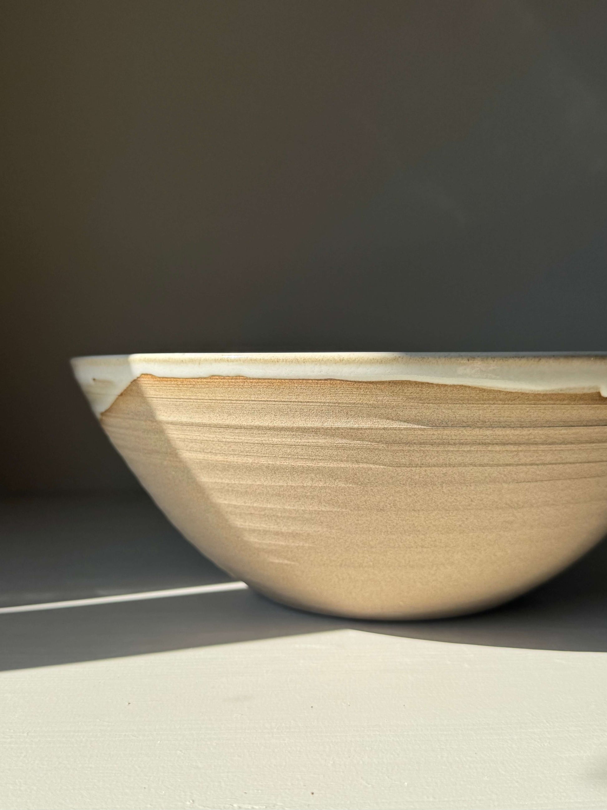 Side view of Large Bowl - Yuki, a handmade ceramic bowl with a white glaze over a raw clay body, showcasing its sculptural and earthy design.