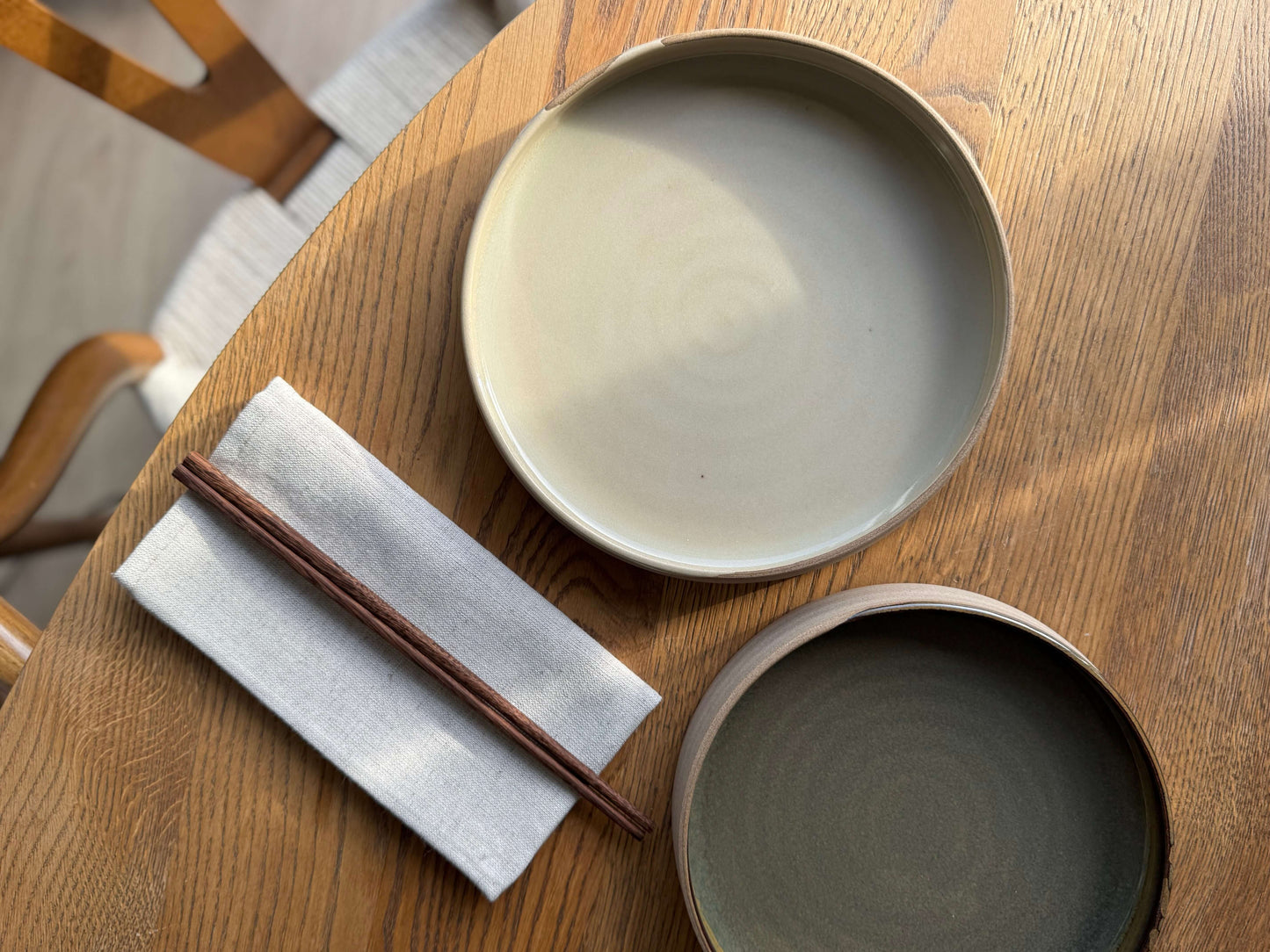Handmade ceramic Large Plate – Inyo Series with glossy clear glaze, showing reflective surface and raw clay edge on a wooden table.
