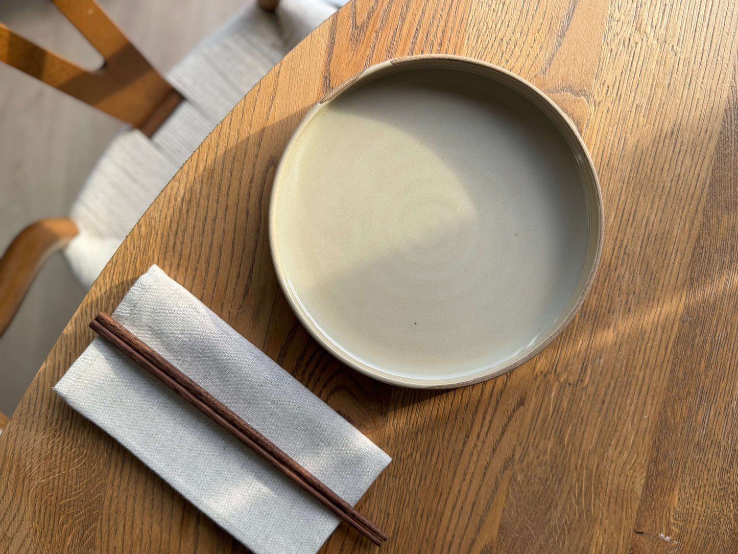 Large Plate – Inyo, handmade ceramic plate with glossy clear glaze on wooden table with chopsticks and napkin, showcasing deep reflective surface.