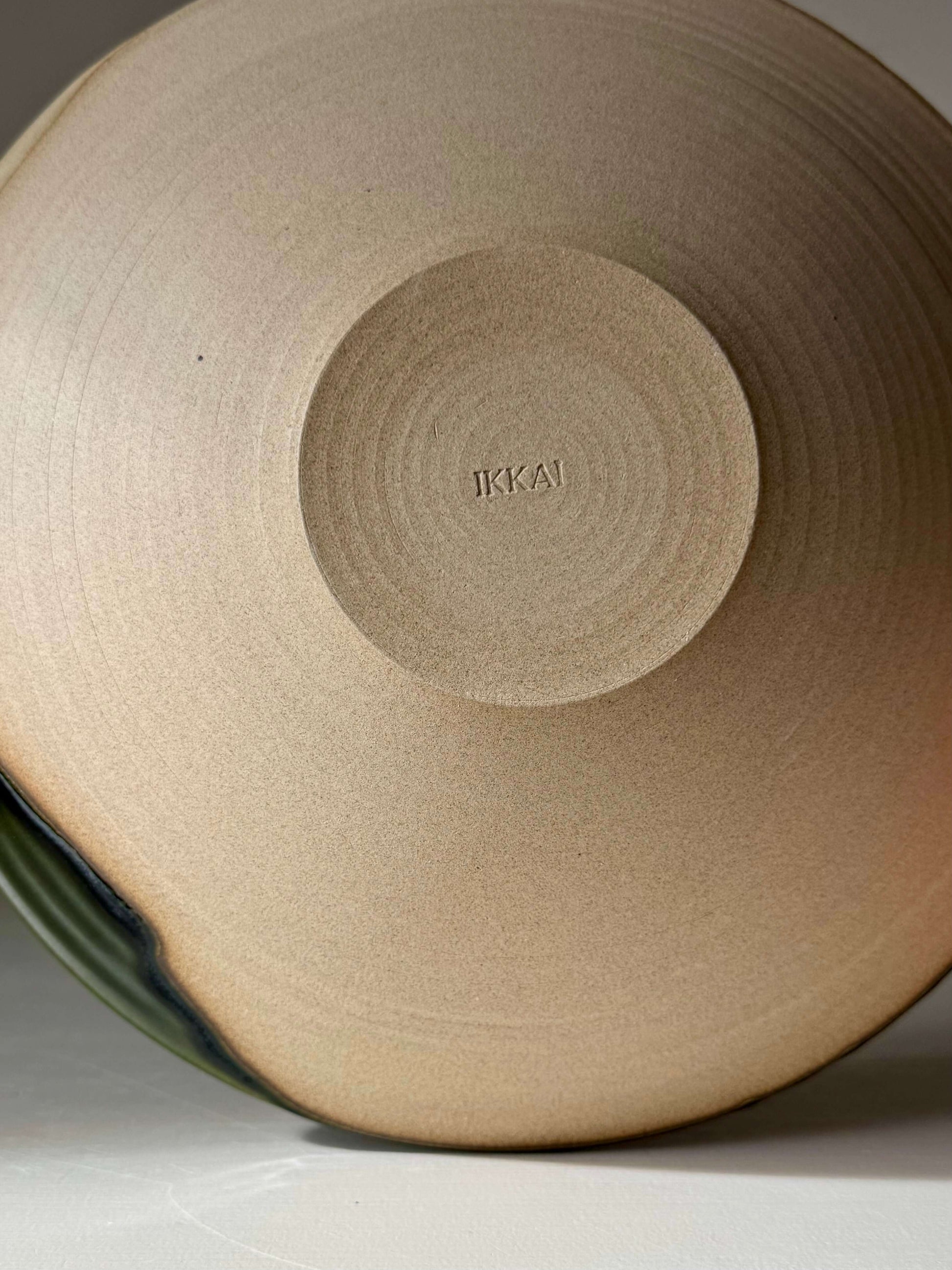 Large Shallow Bowl - Mori Series handmade ceramic base view with flowing green glaze and stamped design.