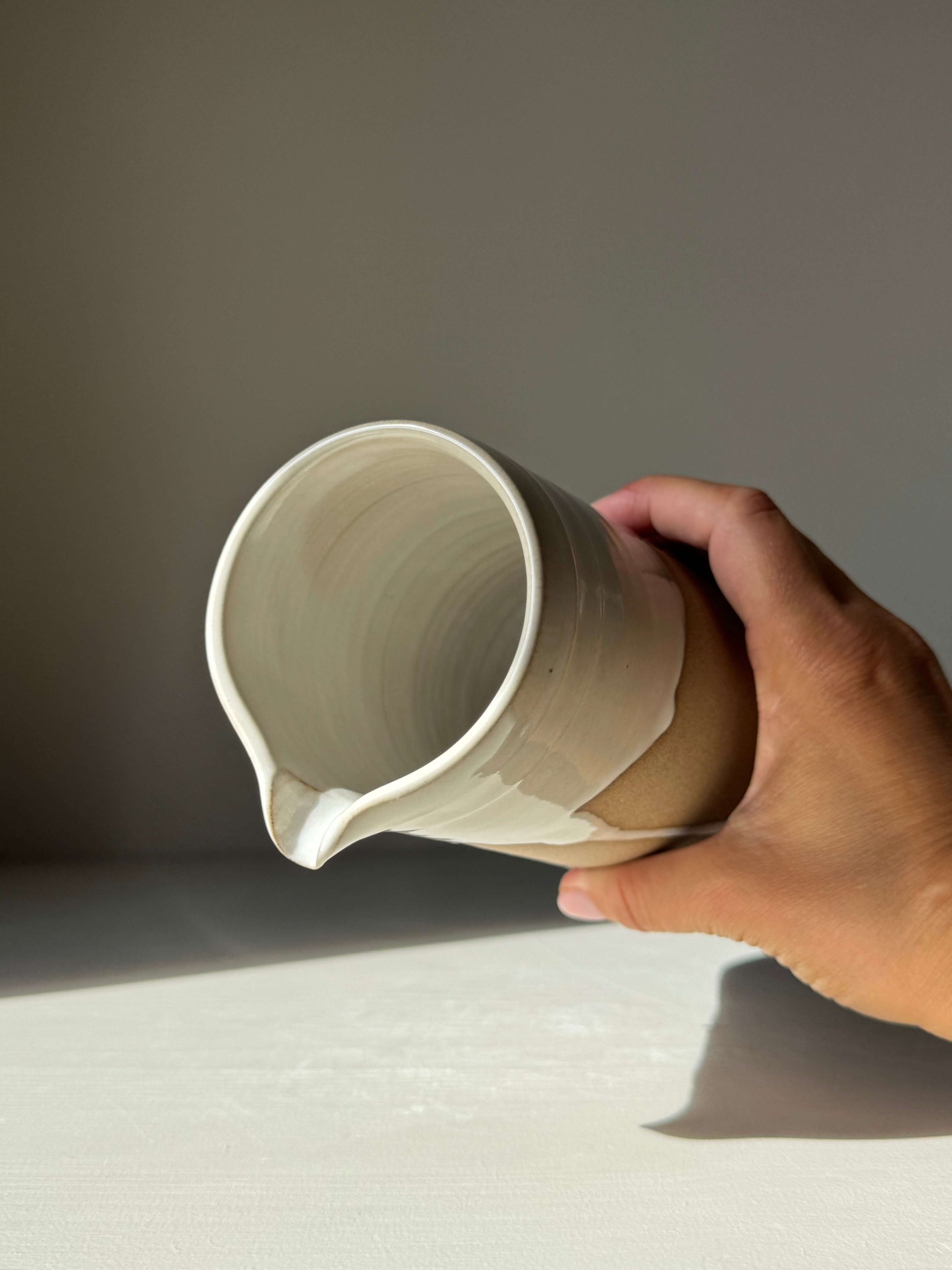 Hand holding Large Vase / Jug – Yuki Series, a handmade ceramic with glossy white glaze and raw toffee clay finish.