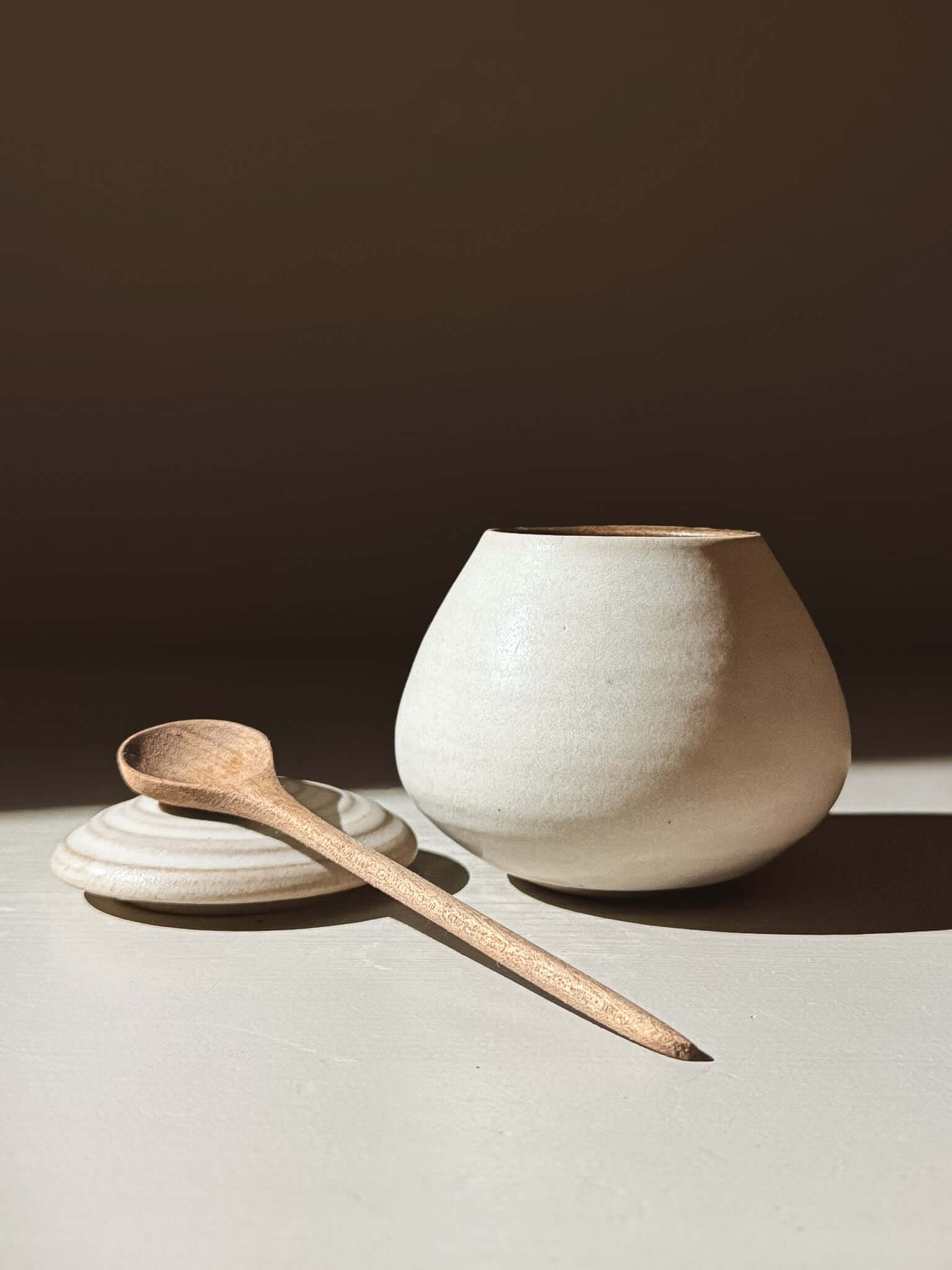 Handmade ceramic Lidded Jar - Eggshell #02 with wooden spoon, perfect for storing everyday treasures, showcasing pottery craftsmanship.