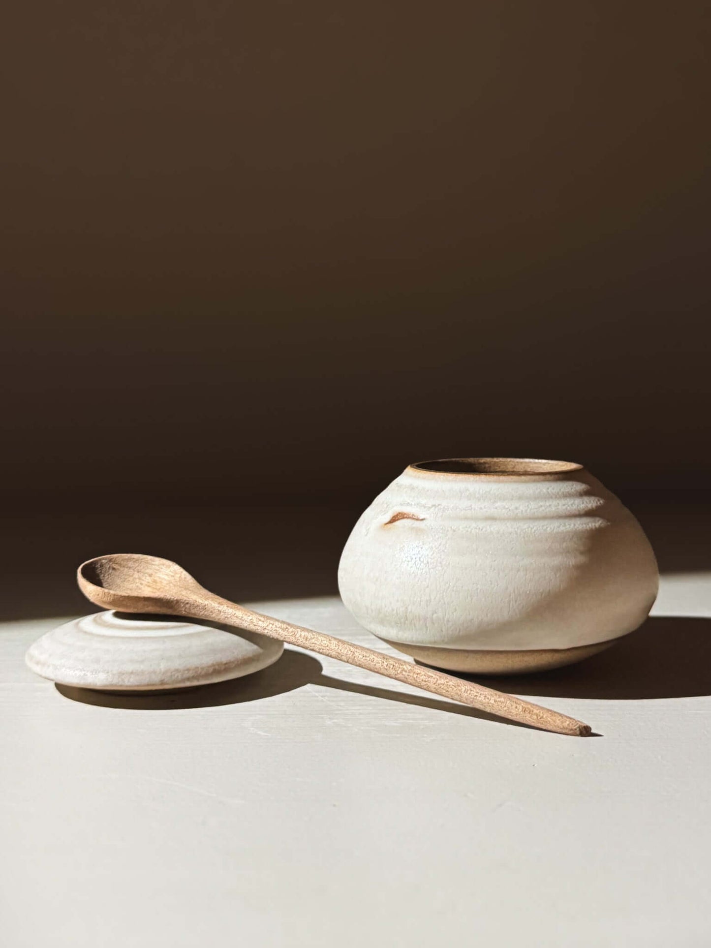 Handmade ceramic Lidded Jar - Eggshell #04 with lid and wooden spoon, showcasing artisanal pottery craftsmanship.