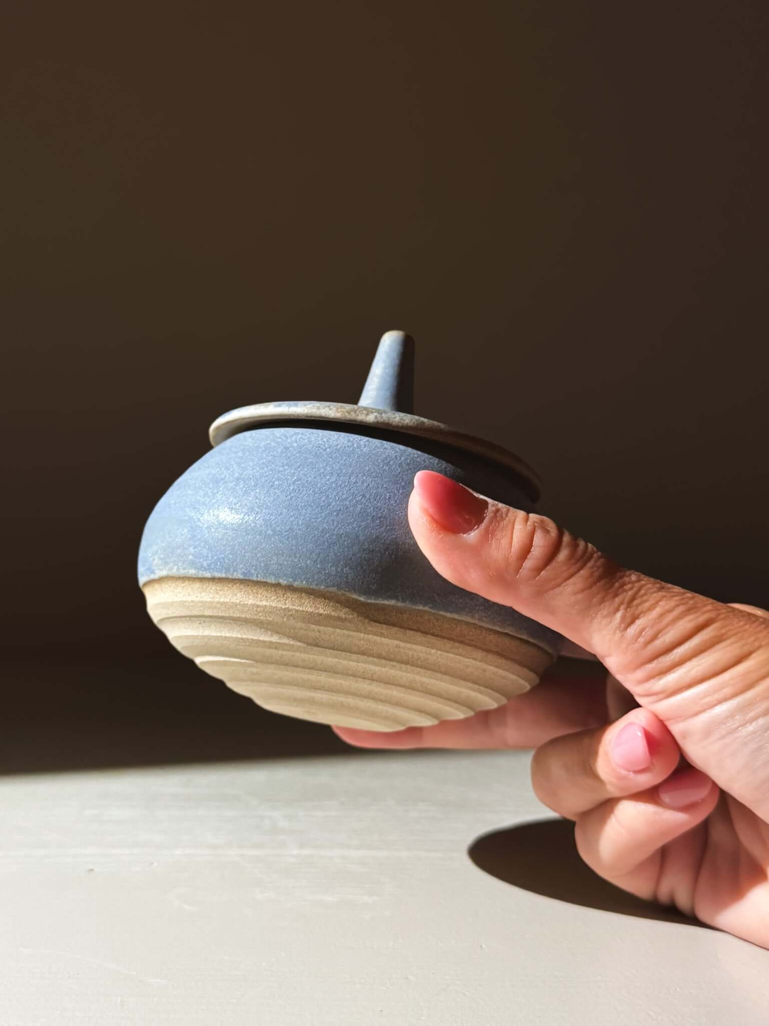 Hand holding Lidded Jar - Mizu #02, a handmade ceramic pottery piece, showcasing its textured design and practical lid.