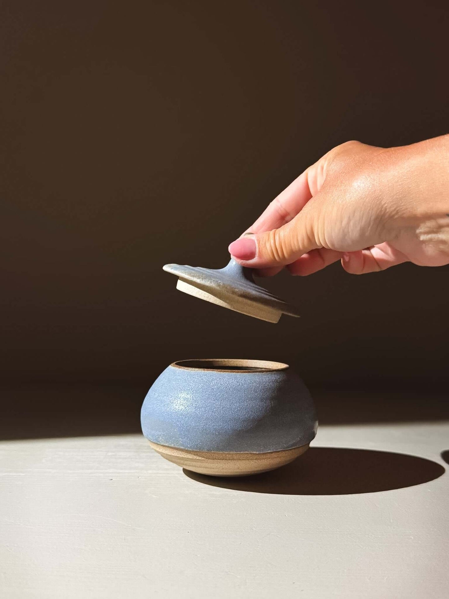 Hand holding lid of Lidded Jar - Mizu #02, a handmade ceramic pottery piece, showing its practical and special design.