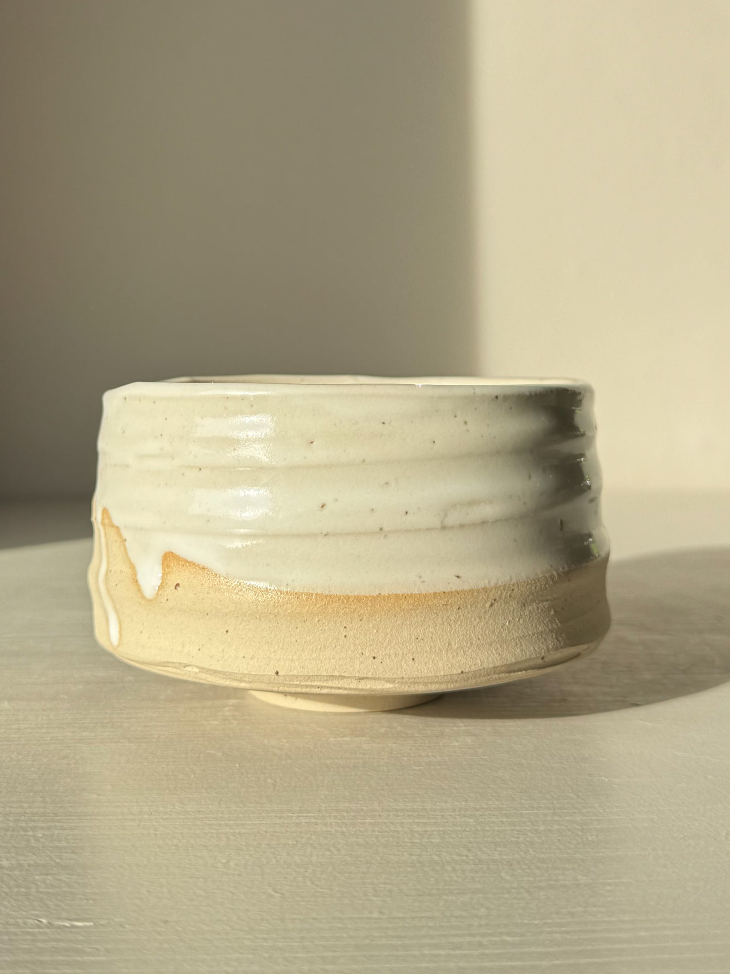 Matcha Bowl – Glossy White #05 made from speckled stoneware clay with a tactile surface, featuring glossy white glaze and exposed raw clay tones.