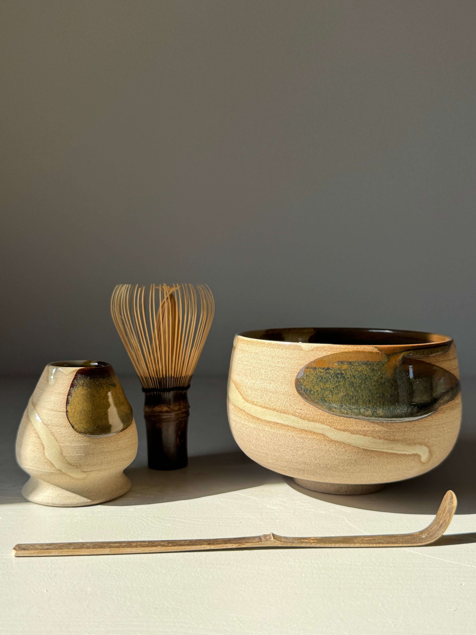 Handmade ceramic Matcha Bowl – Inyo Series #02 with tenmoku and clear glazes, featuring a whisk and chashaku.