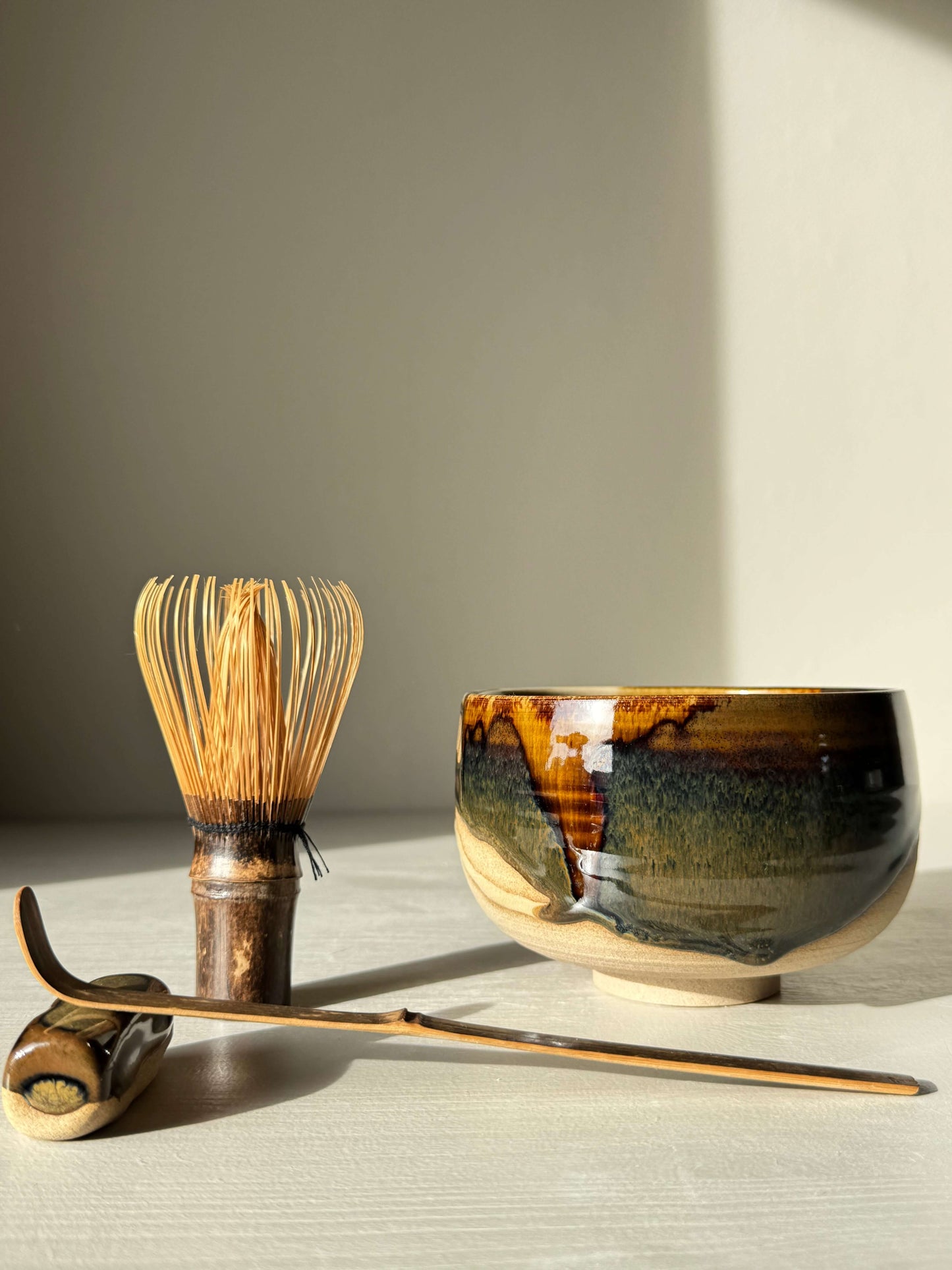 Handmade ceramic Matcha Bowl – Inyo #06 with tea whisk and scoop, featuring dark tenmoku and clear glazes on stoneware clay.