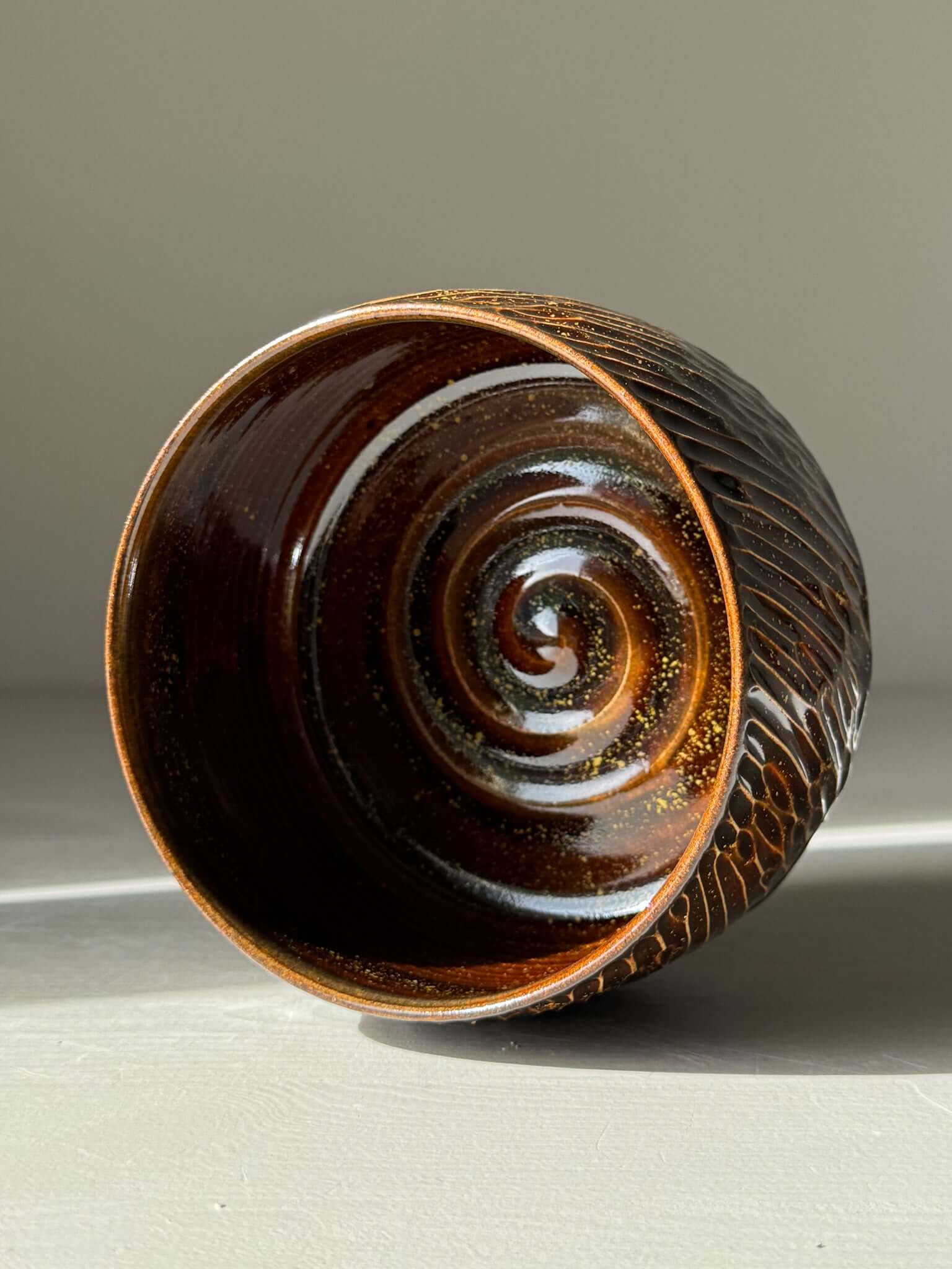 Matcha Bowl – Kinsei #05, handmade ceramic with a spiral of gold and orange glaze, showcasing a rich, glossy brown carved exterior.