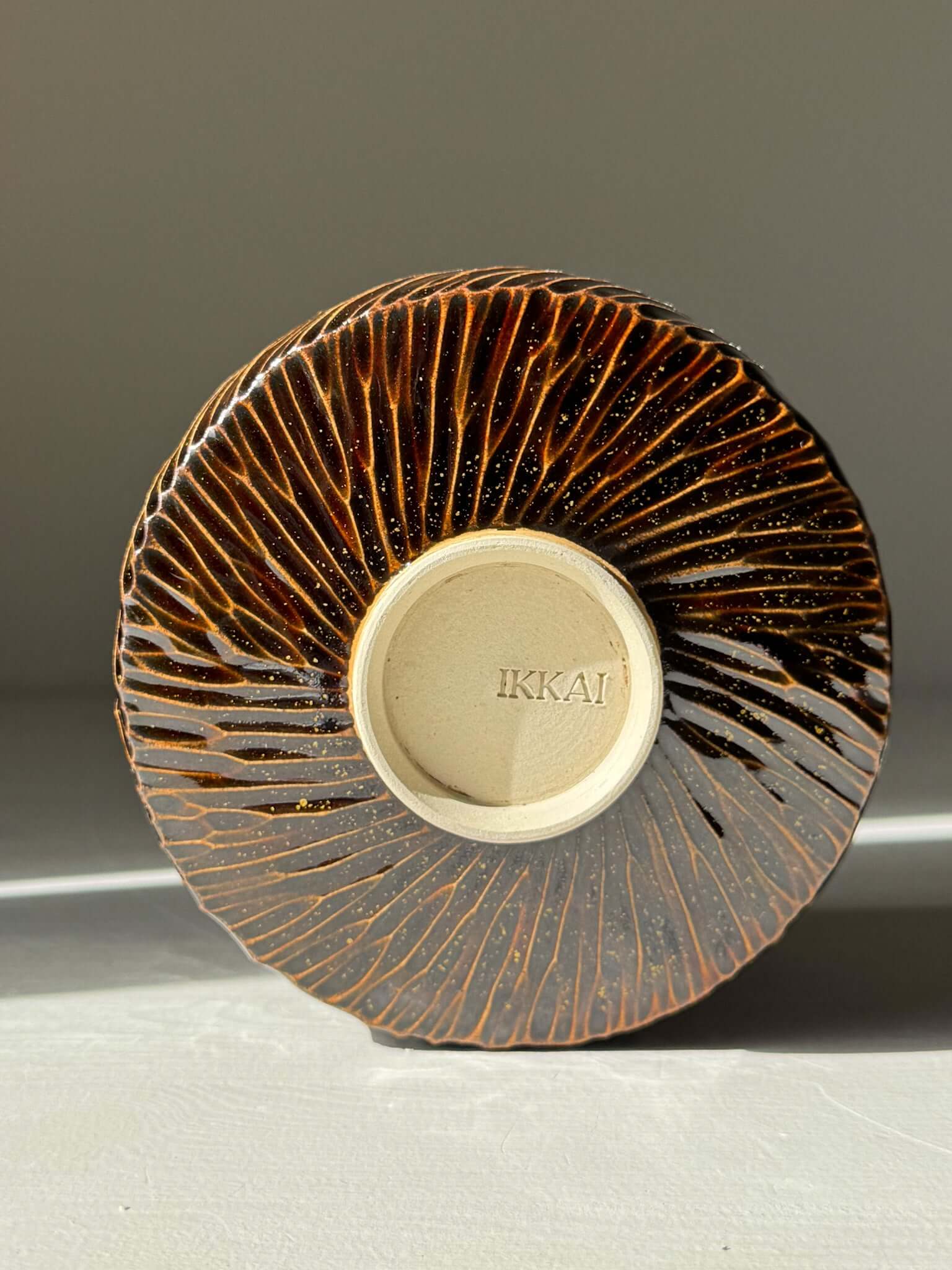 Matcha Bowl – Kinsei #04 handmade ceramic with earthy brown carved exterior, viewed from the bottom, highlighting artistic design.