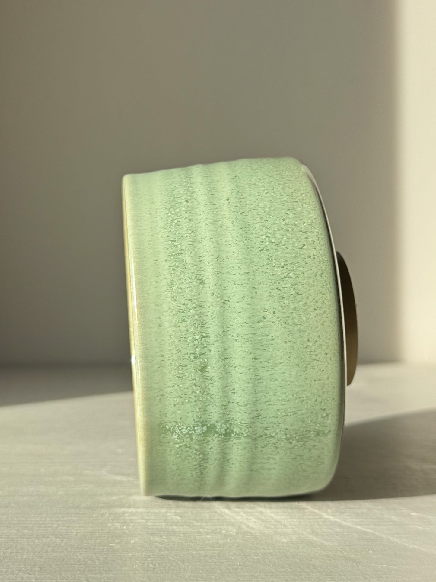 Side view of Matcha Bowl – Sage Glaze #01 with soft sage-green glossy finish highlighting the handmade texture in natural light