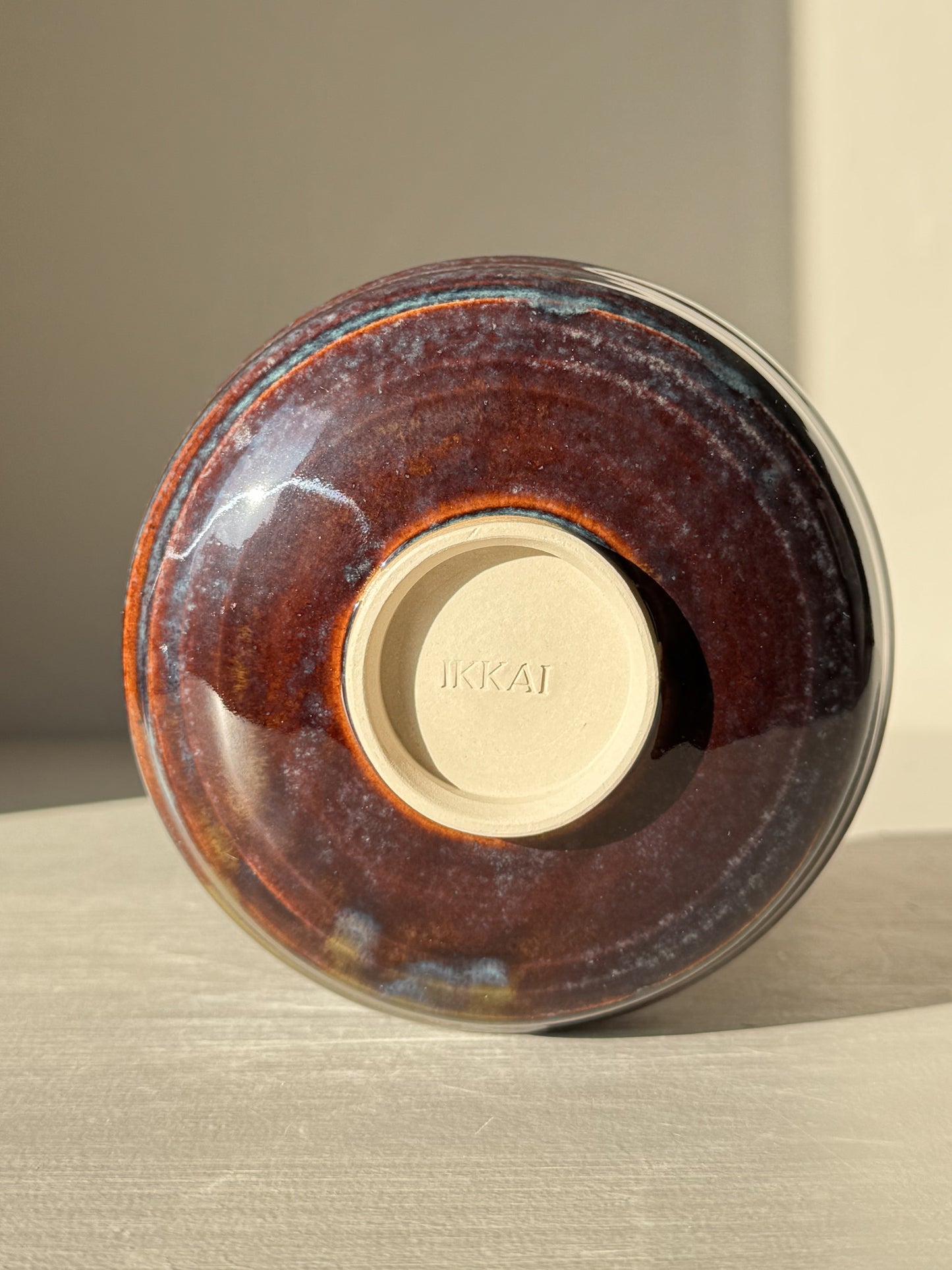 Matcha Bowl Spout - Glossy Blue #01 with earthy tones and flowing blue glaze, viewed from the bottom showing the stamped base and raised foot.