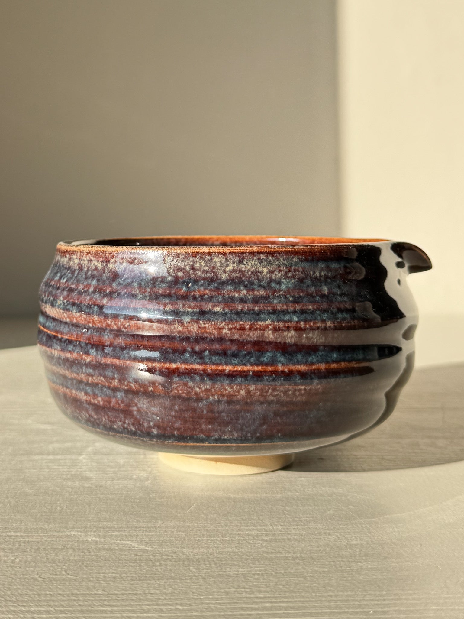 Matcha Bowl Spout - Glossy Blue #01 with earthy tones and flowing blues, featuring a unique asymmetrical design, pouring spout, and raised foot.