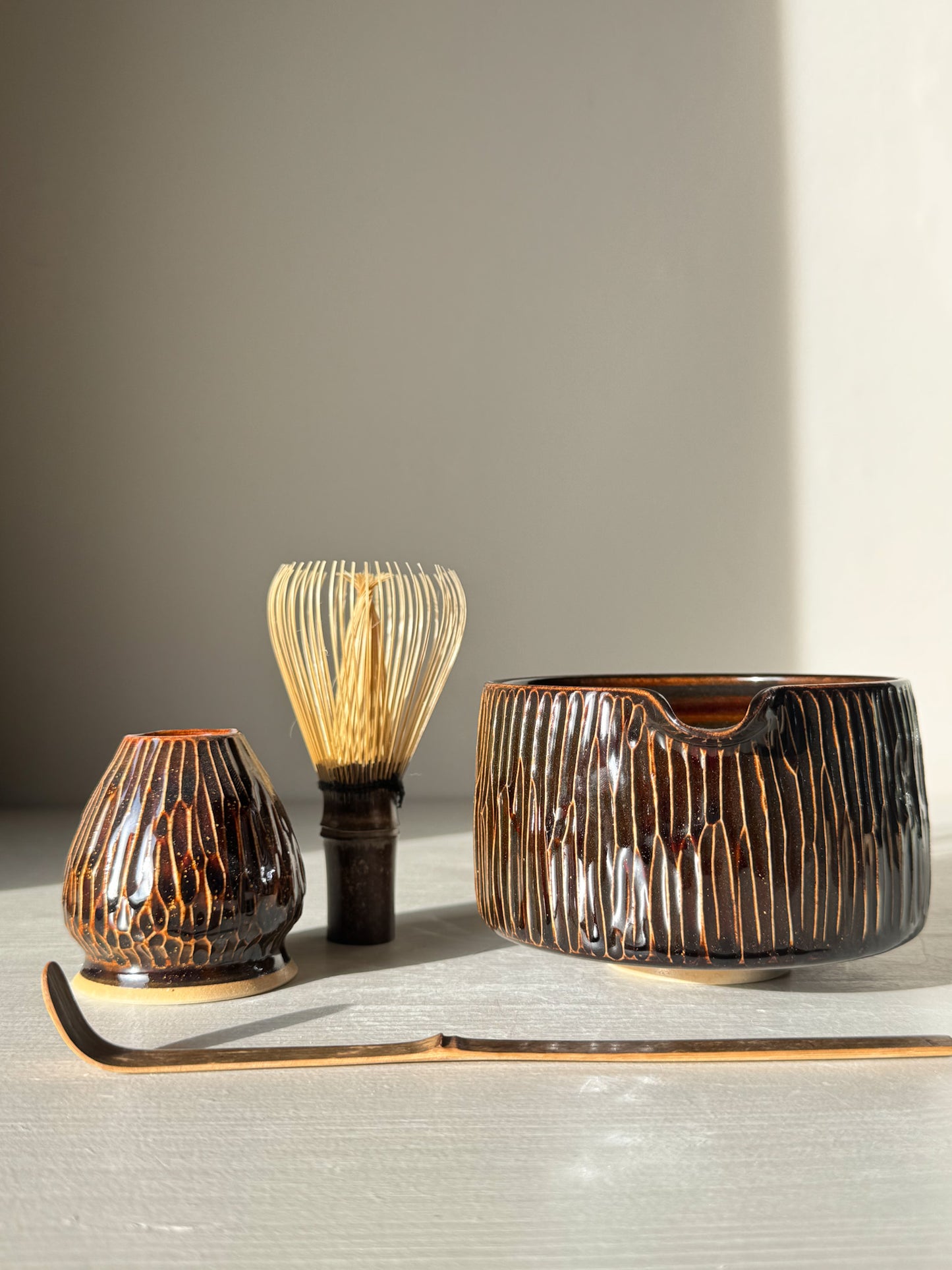 Matcha Bowl Spout – Kinsei #01 with carved design and glaze, complete with whisk and scoop, bathed in sunlight.