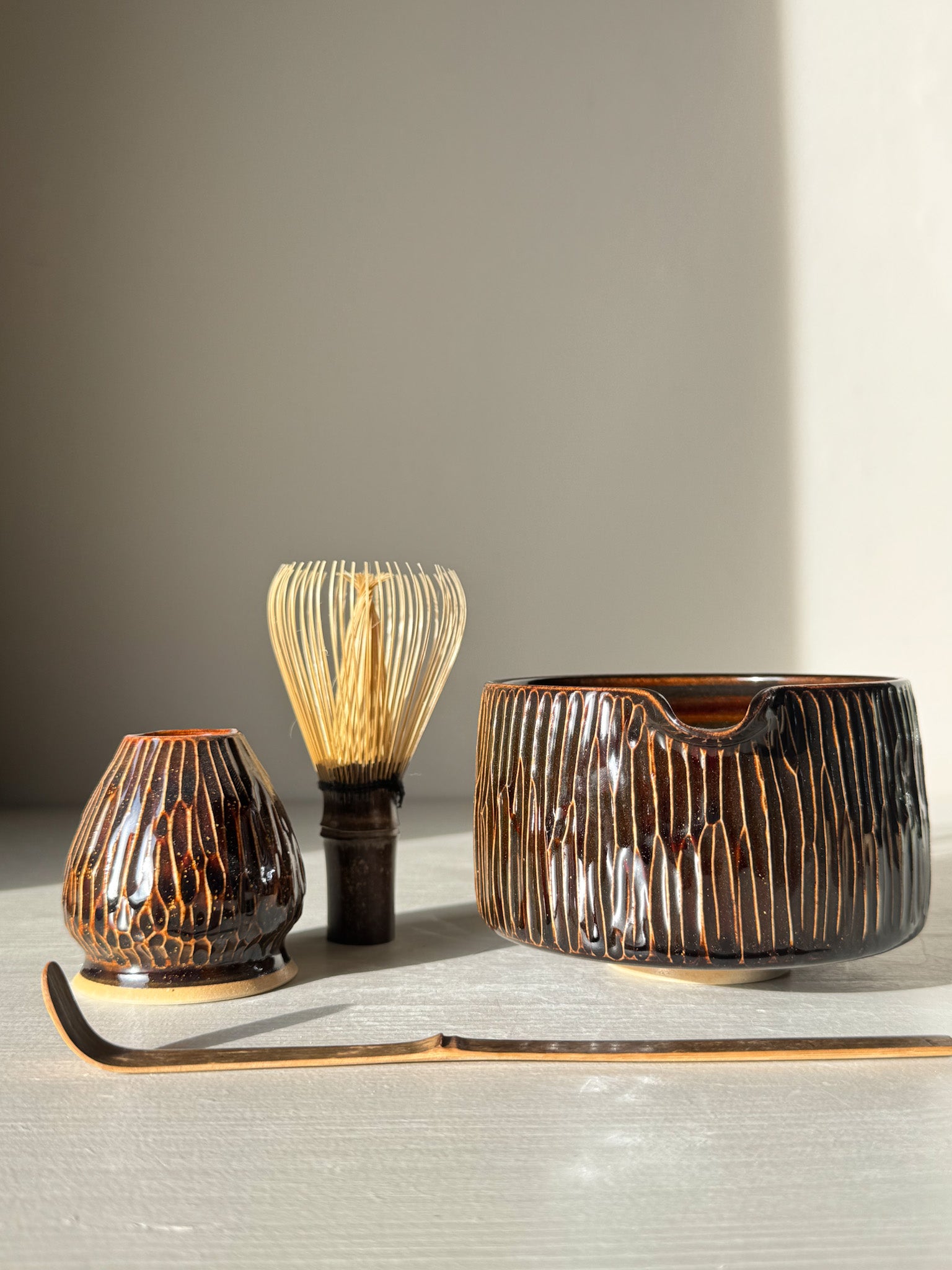 Matcha Bowl Spout – Kinsei #01 with carved design and glaze, complete with whisk and scoop, bathed in sunlight.