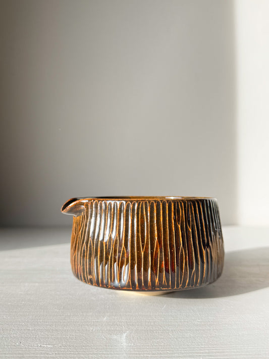 Matcha Bowl Spout – Kinsei #03 with hand-carved vertical lines and golden-brown glaze in sunlight on a table