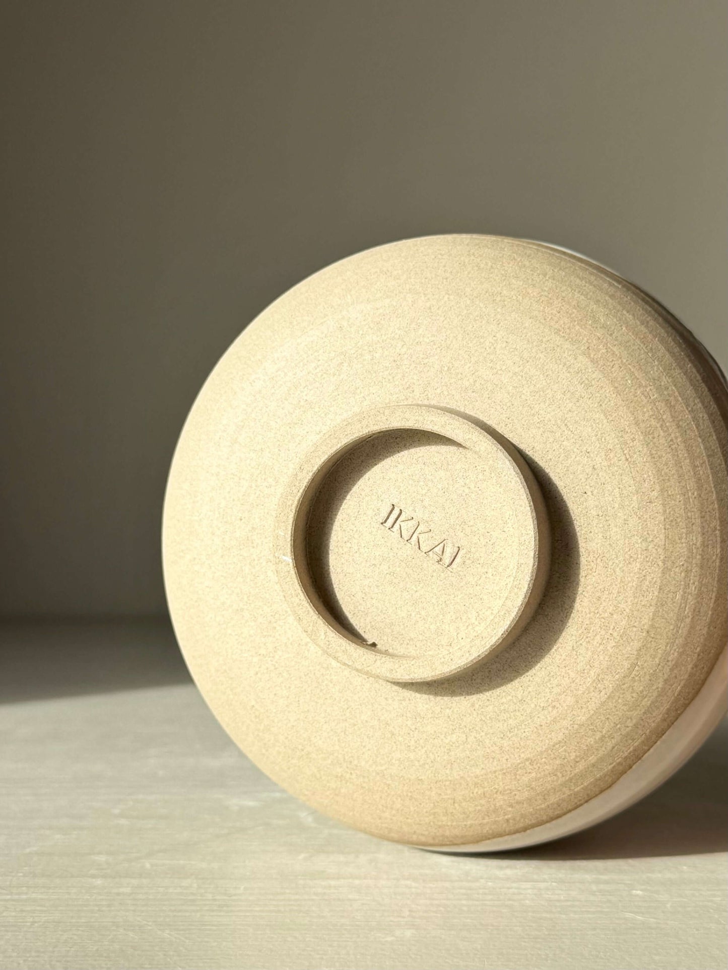 Underside view of Matcha Bowl with Spout – Yuki #03, showcasing handmade ceramic design in toffee clay with IKAI branding.