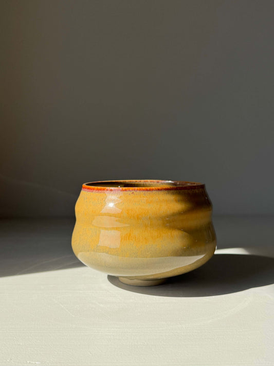Matcha Bowl – Tenmoku Glaze in handmade ceramic with flowing ridges, reflecting warm browns and deep blacks, showcasing a glossy surface.